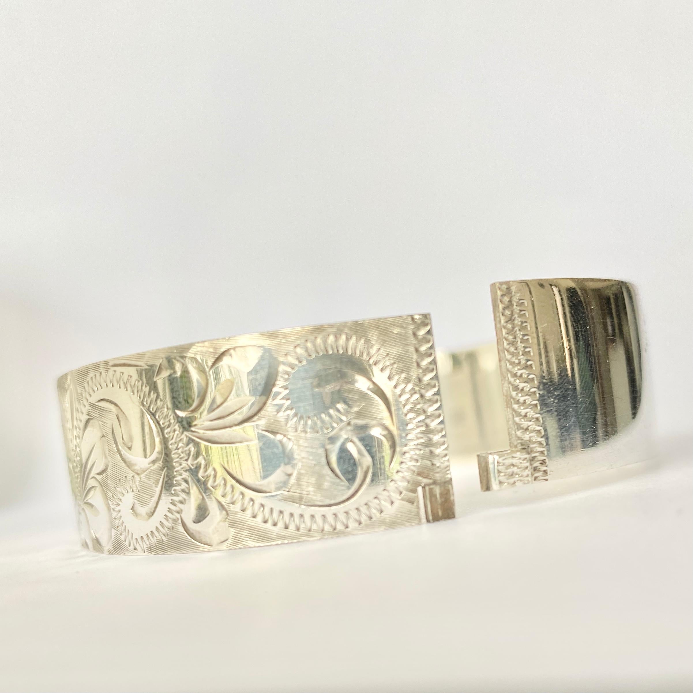 Deeply and intricately engraved on the front panel of this bangle is a classic swirl and textured design. Hallmarked Birmingham 1974. 

Inner Diameter: 60mm
Bangle Width: 16mm 

Weight: 35.9g