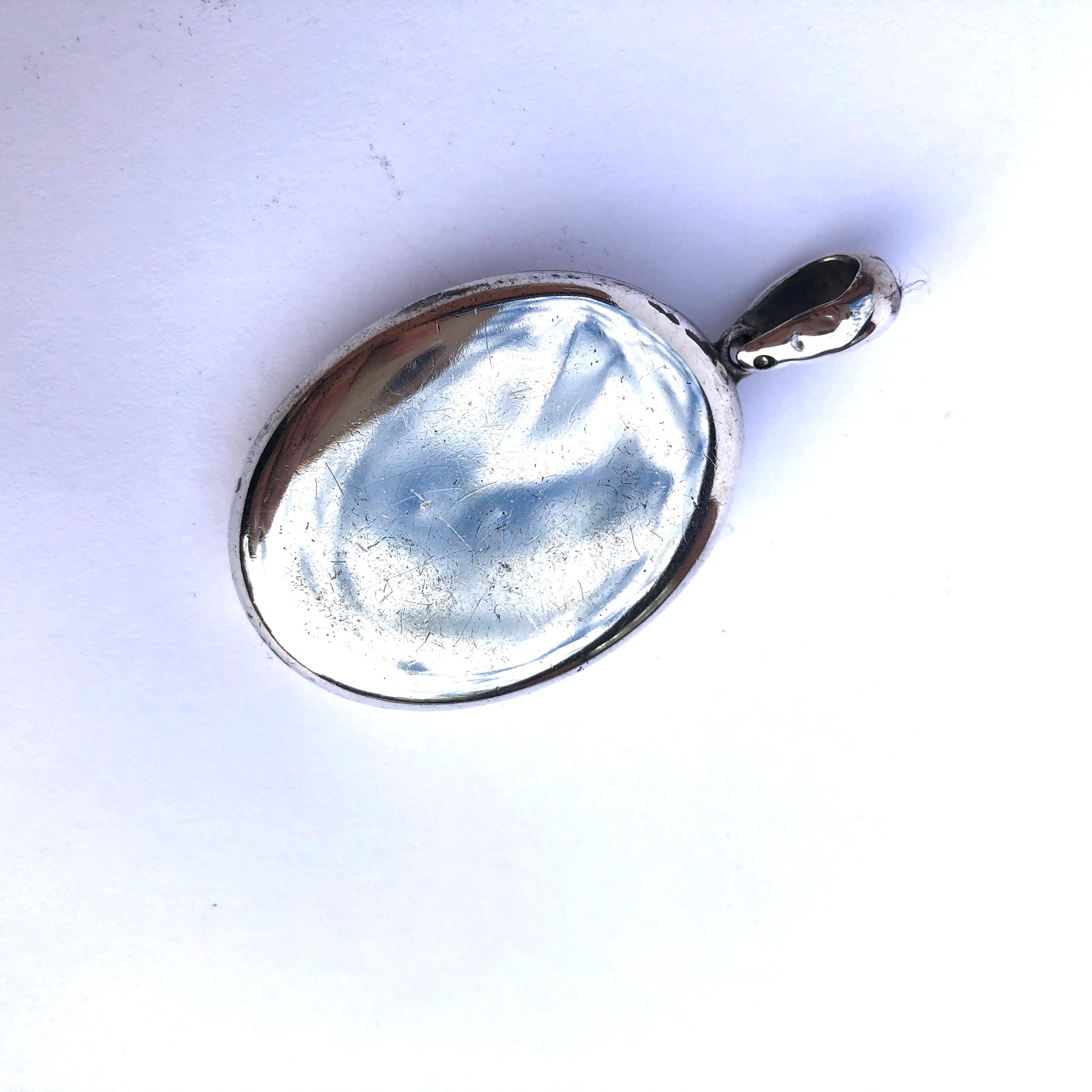 This silver locket is so glossy and beautiful. The front of the locket has the letters R H C engraved in a very fancy manner! This particular locket still holds two sweet photographs of a loved one. 

Dimensions From Loop: 50x 27mm 

Weight: 20.8g