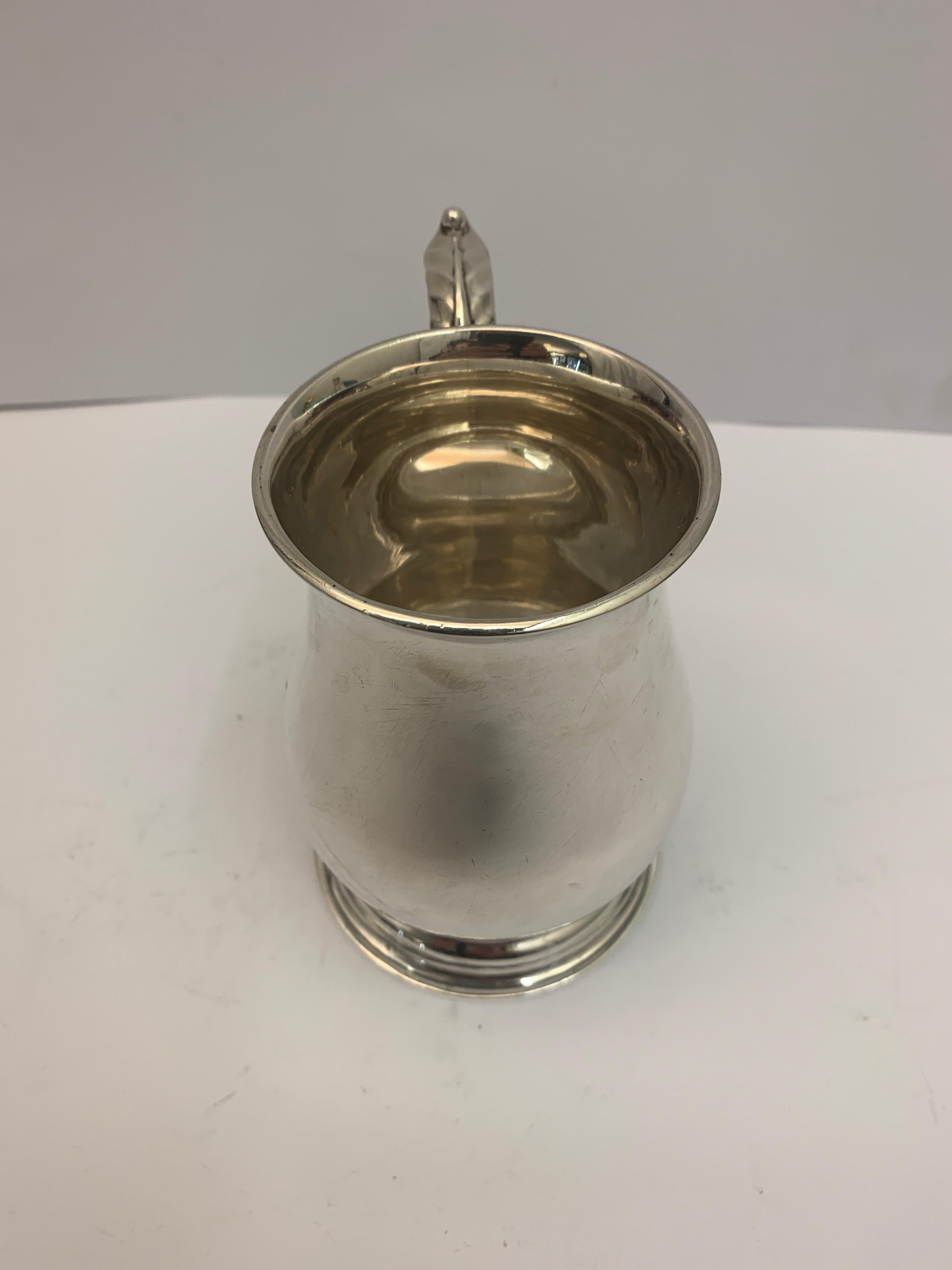 A small antique silver mug with a decorative scroll and leaf style handle. Made in 1910 by John Edward Wilmot. Fully Hallmarked Birmingham.