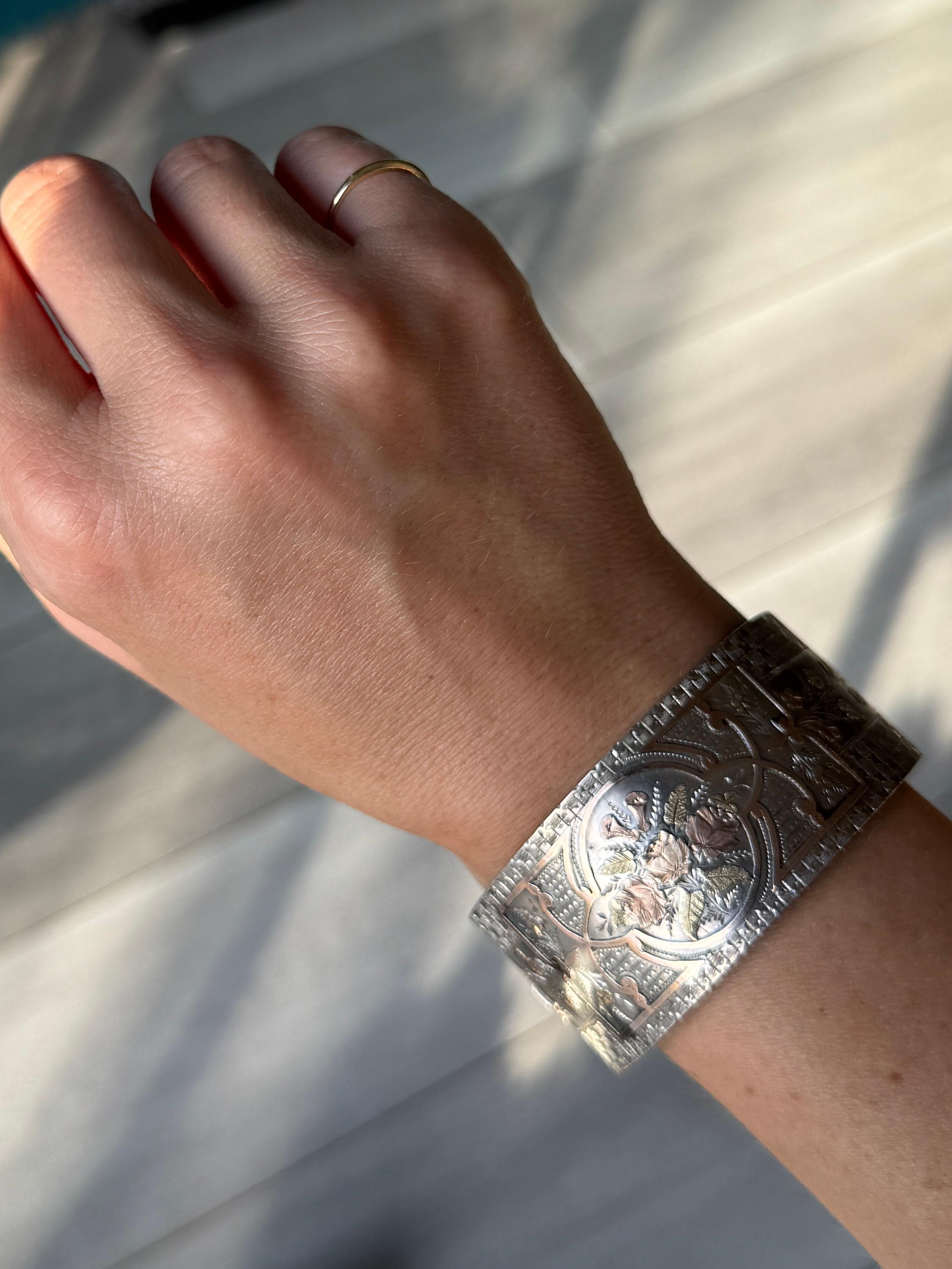The detail on the front of this silver bangle is of roses, leaves and other beautiful flowers.

Inner Diameter (hinge to clasp): 5.5cm
Inner Circumference: 17cm
Bangle Width: 28mm 

Weight: 26.5g