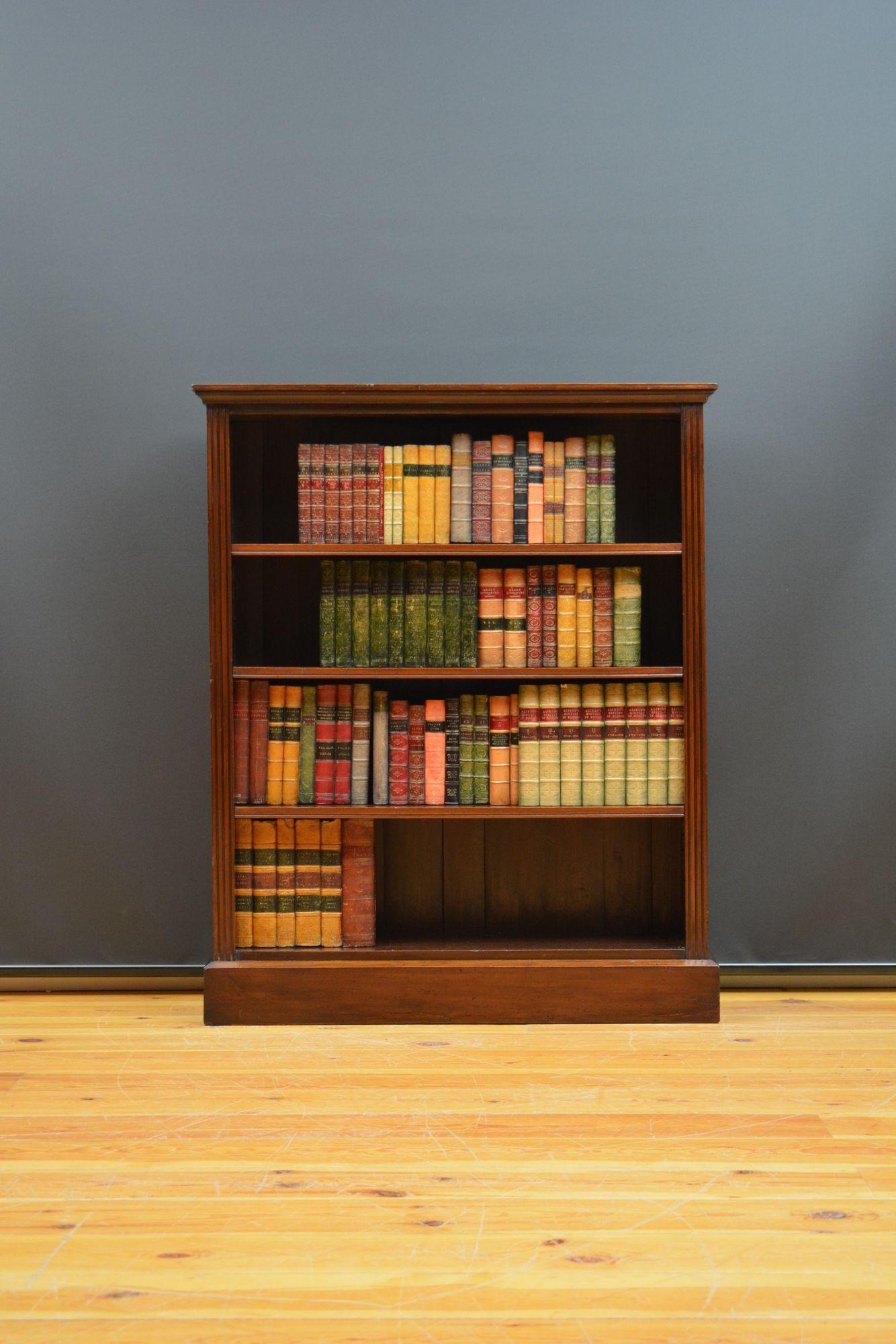Sn5616 English Edwardian open bookcase in solid mahogany, having oversailing top with chamfered edge above three height adjustable shelves flanked by fluted pilasters, all standing on moulded plinth base. This antique bookcase retains its original