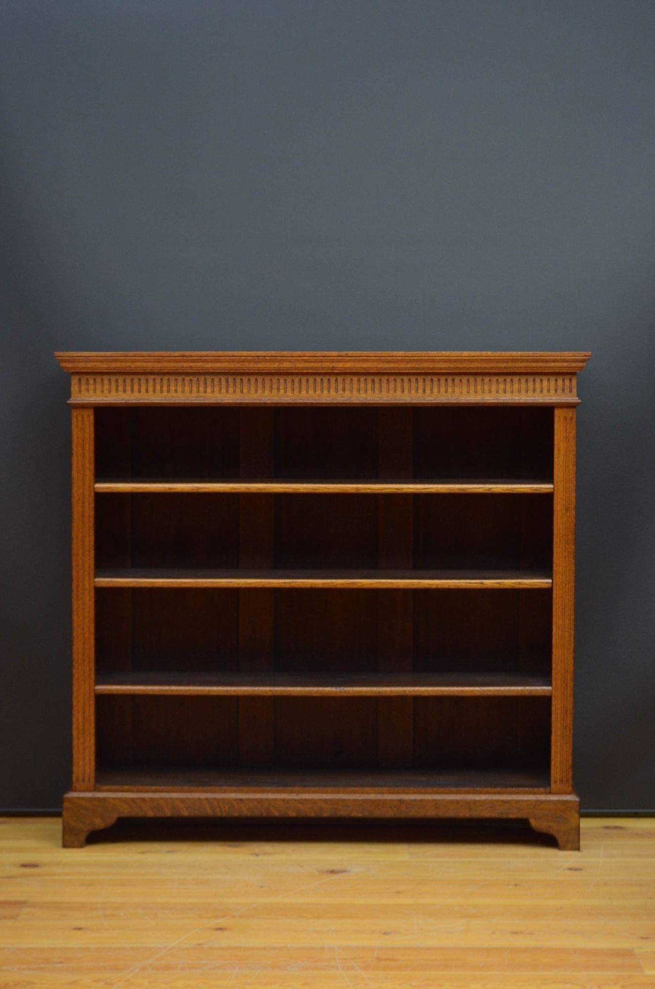 J036 Edwardian open bookcase in oak, having over sailing top with moulded edge above reeded frieze and three height adjustable shelves, all flanked by reeded uprights, standing on shaped plinth base. This antique bookcase is in home ready condition.