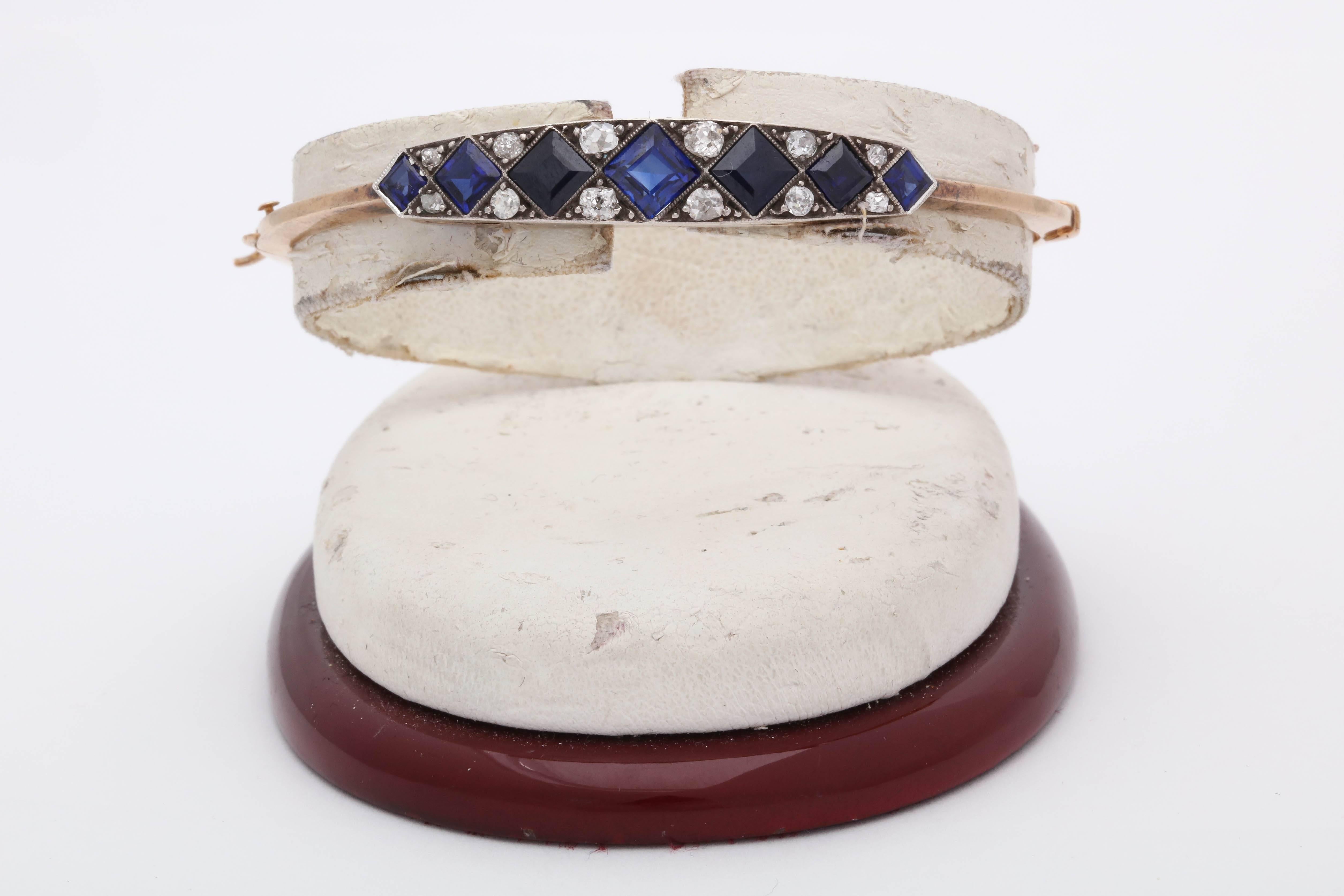 One Ladies Edwardian Bangle Style Bracelet Created In 18kt Yellow Gold With A Platinum Setting On Top. Bangle Bracelet Is Embellished With Seven Custom Design Step Cut Sapphires Weighing Approximately 1.75 Cts And Also Designed With Twelve Mine Cut