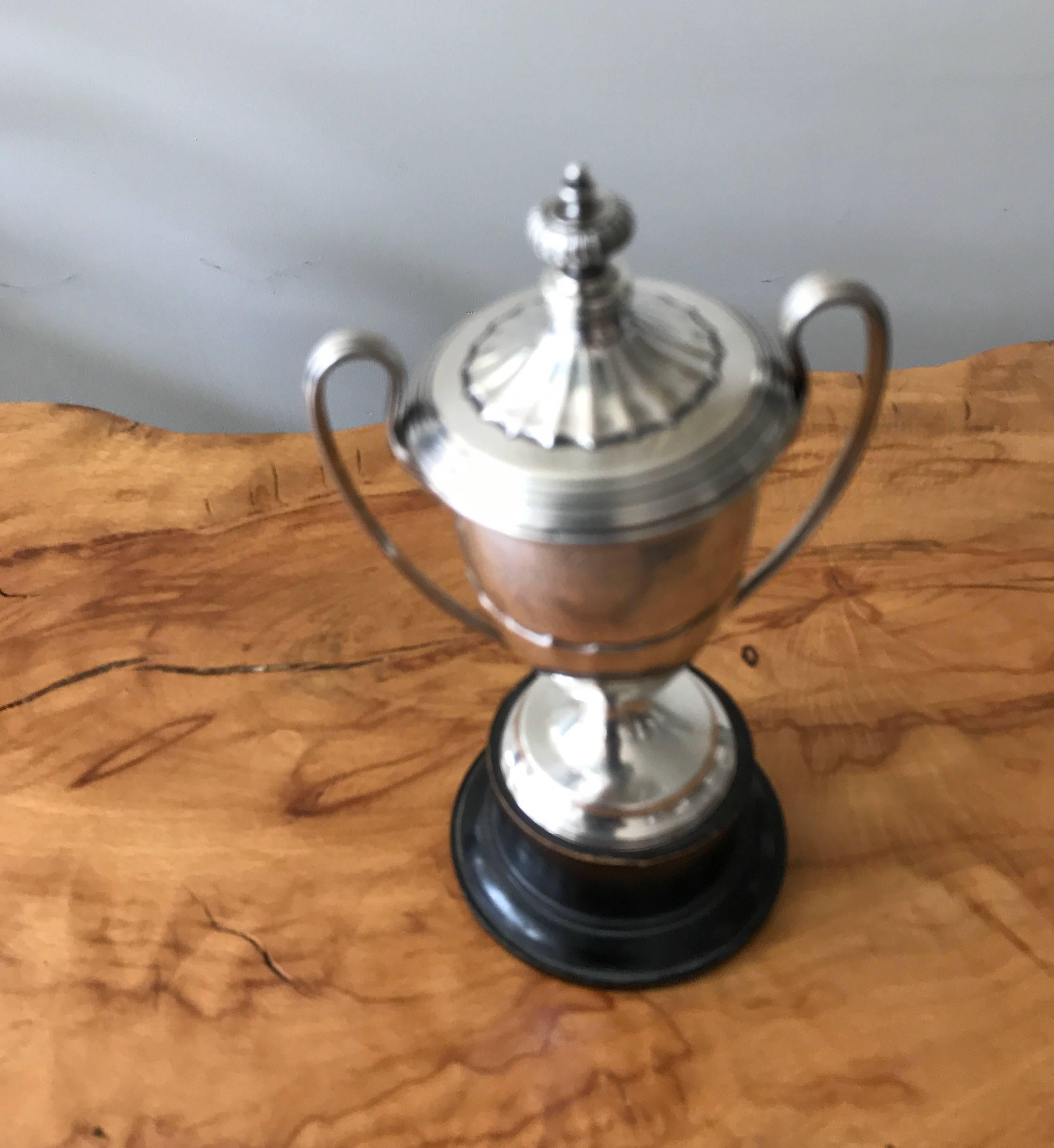 A remarkable 1920s sterling silver English trophy presentation cup. The lidded trophy has loop handles and an ebony wood base.
Bearing full London hallmarks. The dedication reads 