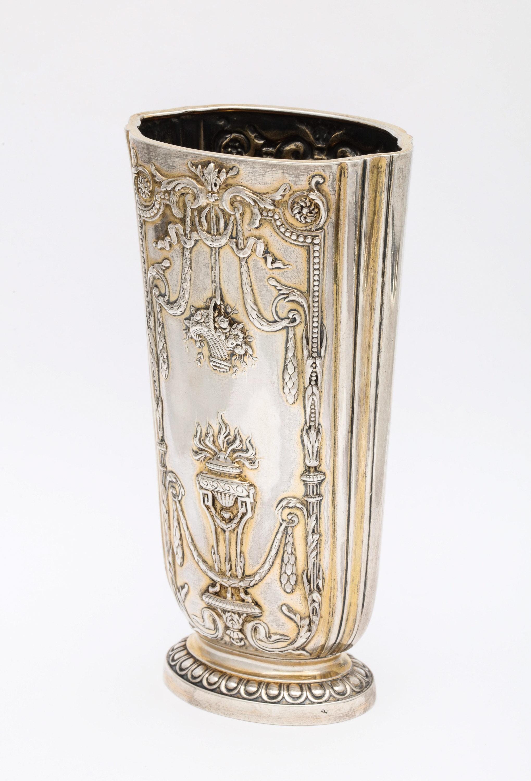 Edwardian, sterling silver-gilt vase, Paris, circa 1905. Decorated with baskets and torchieres. Measures: 5 1/2 inches high x 2 3/4 inches wide (at widest point) x 2 inches deep (at deepest point). Lightly gilded. Weighs 4.845 troy ounces. Dark
