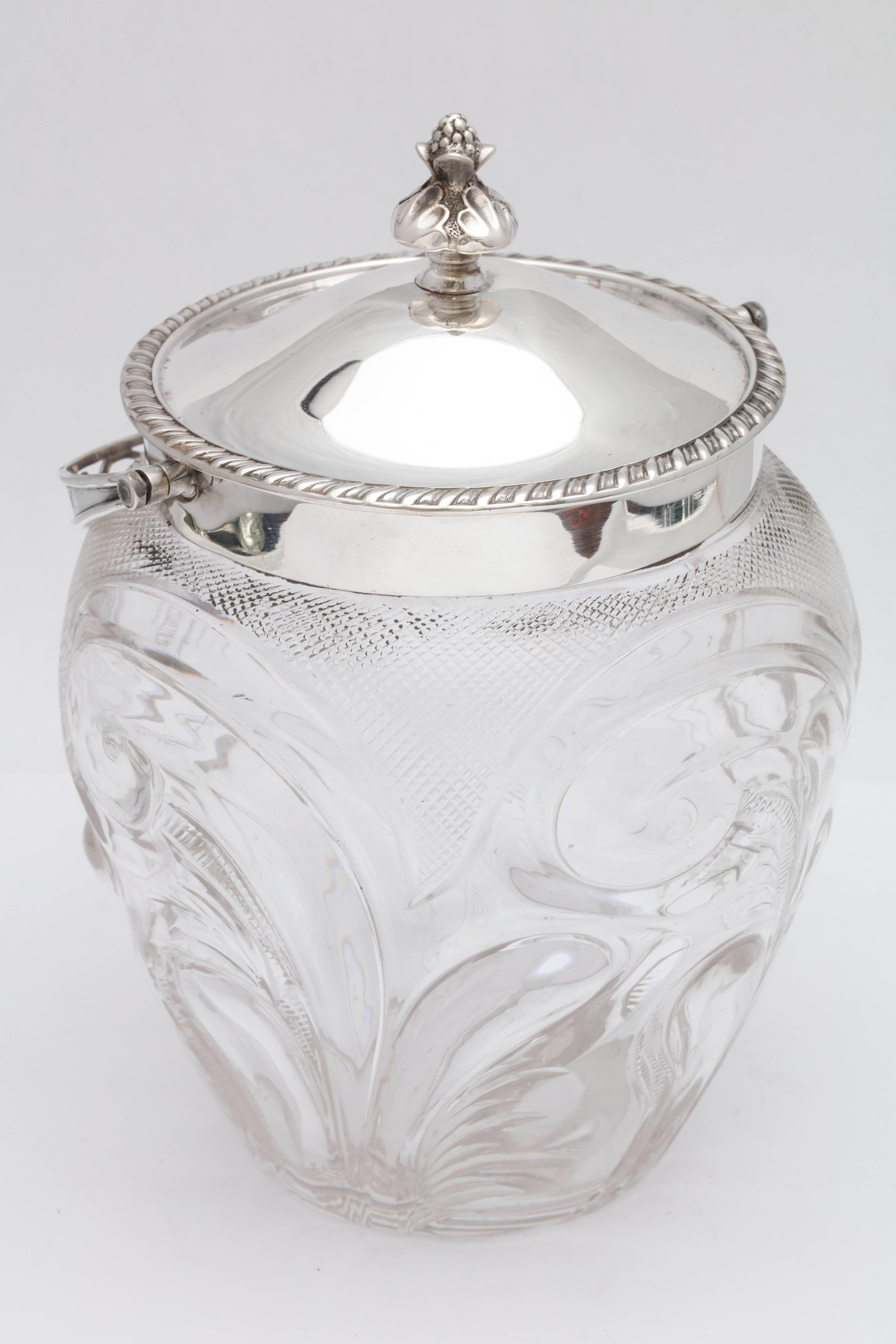 Edwardian, sterling silver-mounted, cut glass biscuit barrel/ice bucket, Sheffield, England, 1901, Walker and Hall - makers. Lovely teardrop shaped barrel has swirled and diamond-cut designs; lid has a reeded border; handle is pierced. Vacant