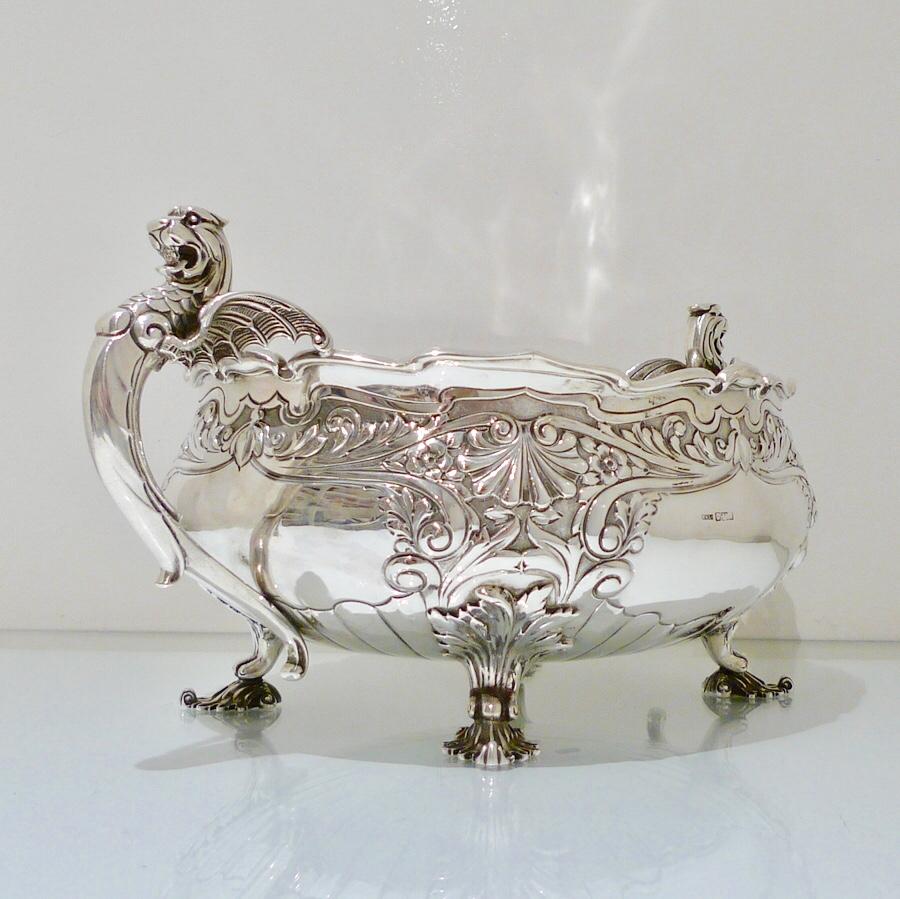 A large and extremely decorative sterling silver oval jardinière, decorated with ornate embossing to the upper bowl. The handles are magnificently designed as “griffins” and the underside of the bowl has elegant flute designs for lowlights.

