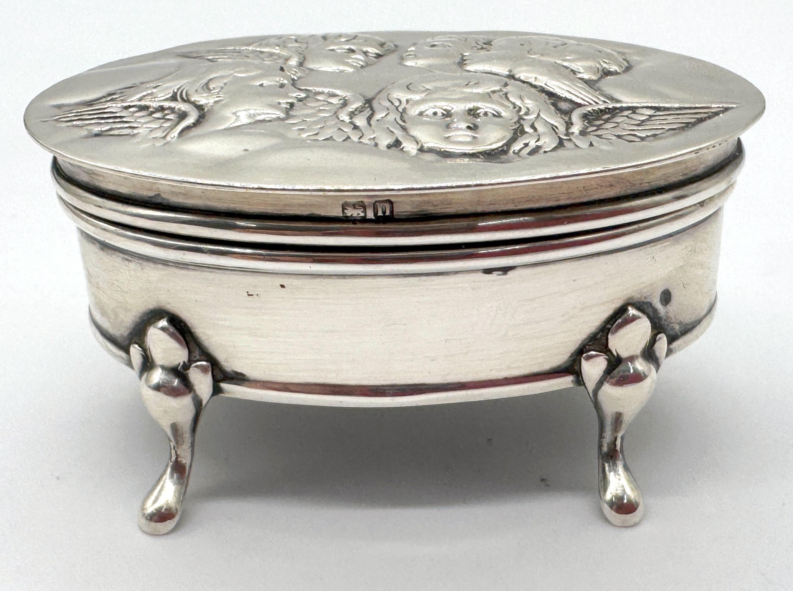 Edwardian Sterling Silver Oval Trinket Box with Raphael Angel Heads, Birmingham 1912, 66 grams with velvet and leather interior 

Maker: Thomas Sidney Buckler (T.S.B.)
Assay Office: Birmingham
Date of Letter: 1912
Dimensions: 2.75