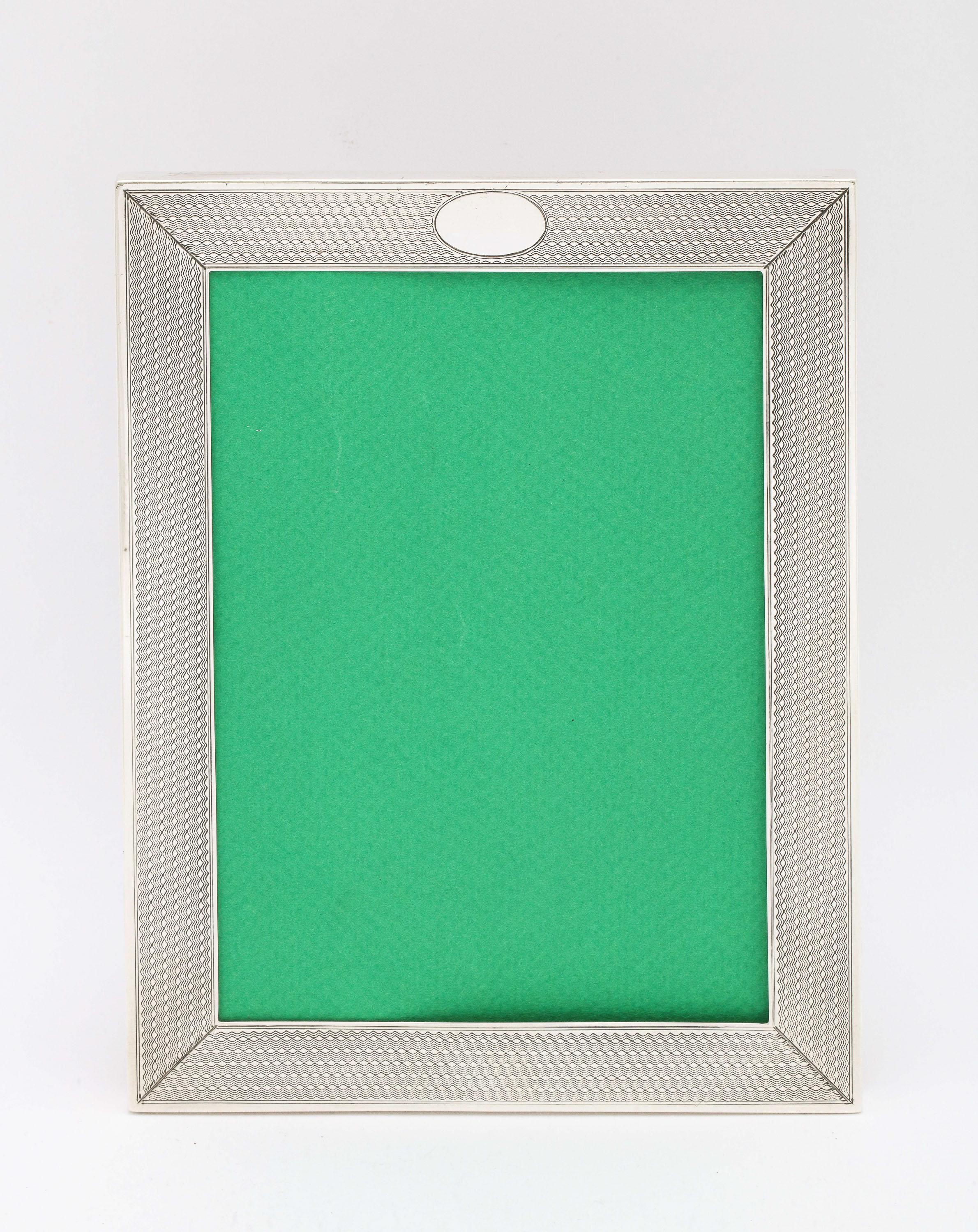 Edwardian, sterling silver picture frame with velvet back, Birmingham, England, year-hallmarked for 1910, L. Emmanuel - maker. Engine-turned design. Vacant cartouche. Outer frame measures 5 inches by just under 6 3/4 inches wide x 4 inches deep when