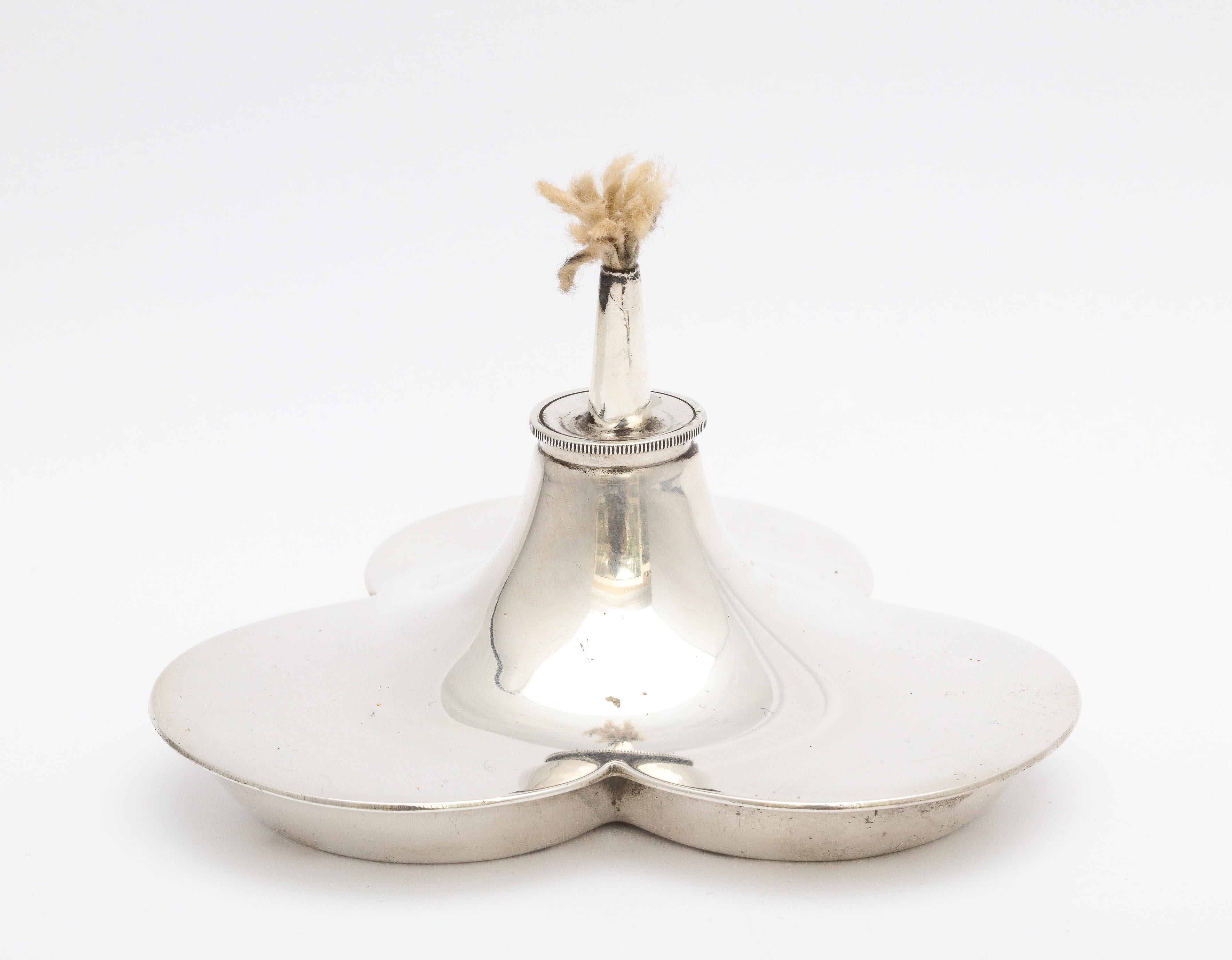 Encendedor de mesa eduardiano de plata de ley con forma de trébol, Birmingham, Inglaterra, 1914, John Collard Vickery - fabricante. Medidas: 3 3/4 pulgadas de ancho x 3 3/4 pulgadas de profundidad x 2 1/2 pulgadas de alto. Pesa 2,670 onzas troy.