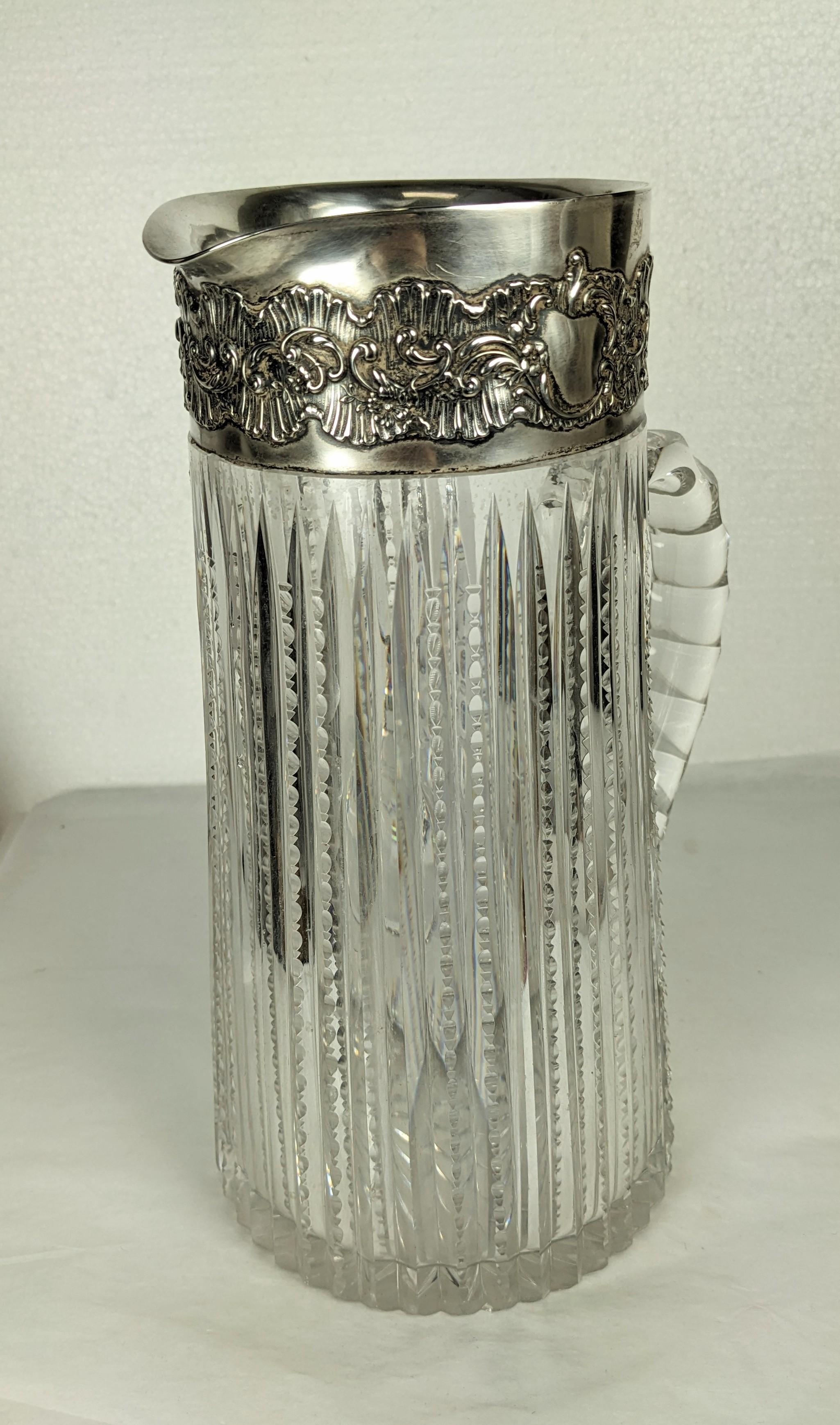 Elegant Edwardian Sterling Trimmed Cut Crystal Pitcher from the late 19th, early 20th Century. Striated Cut crystal carved with small divet patterns which are echoed on the handle. Sterling rim with Victorian floral panel. 1880s-1900's USA. 
Marked