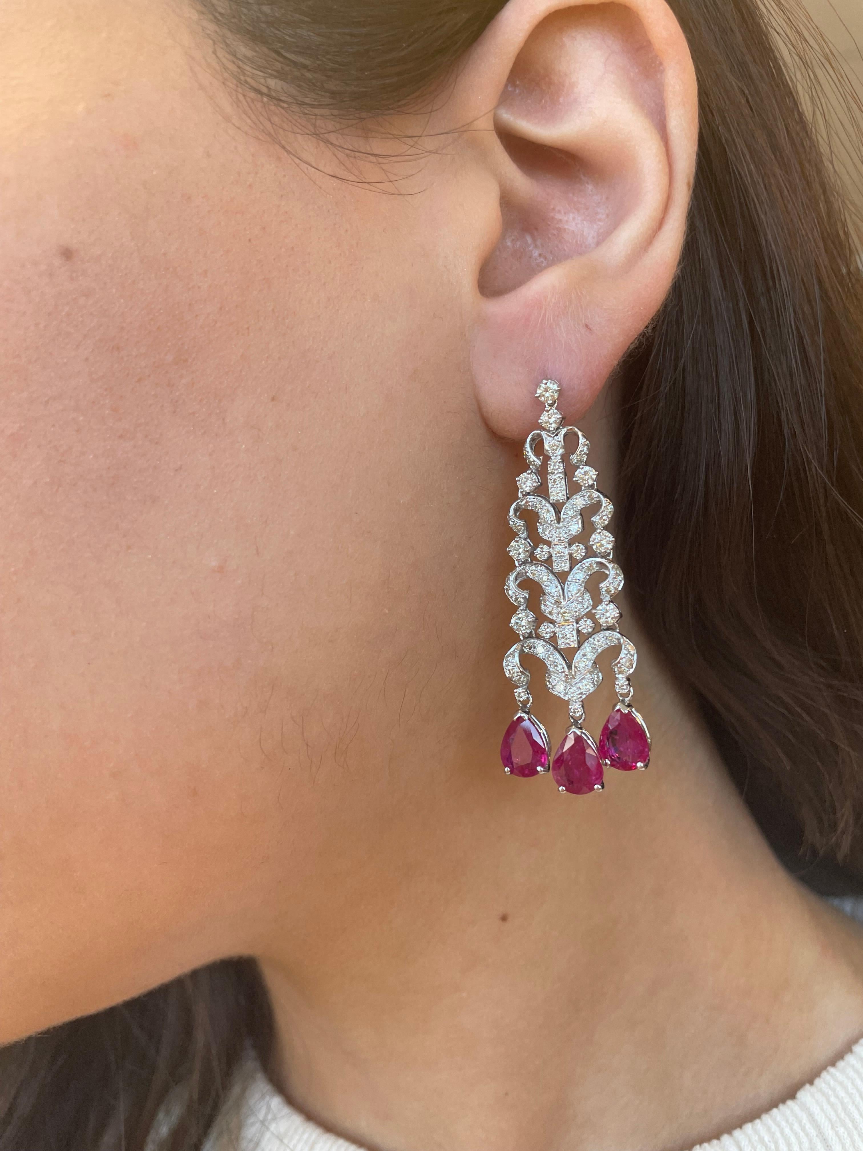 Stunning Edwardian inspired bezel set chandelier earrings.
6 pear shape rubies heat, 7.12 carats. Complimented by round brilliant diamonds, 3.06 carats. Approximately G/H color grade and SI clarity grade. Prong set with milgrain work, 18k white