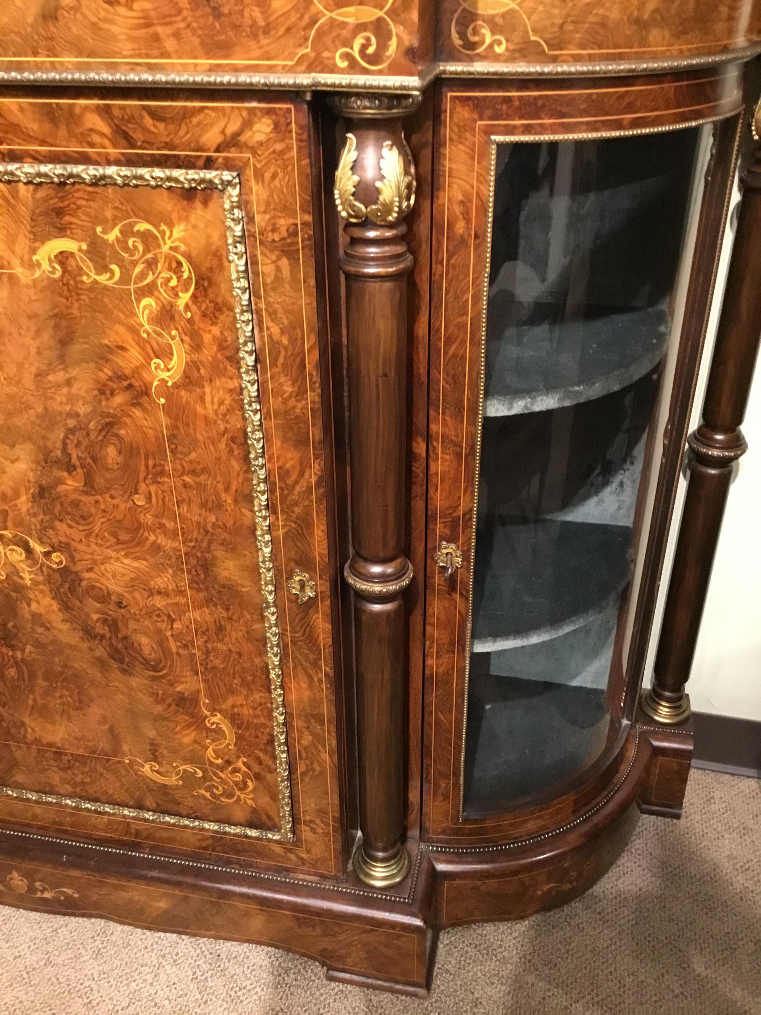 Antique burled walnut cabinet in lovely condition with side opening glazed doors for display.
The center door opens with original locks for storage. The cabinet has been polished and has
a beautiful patina. Columns down each side enhance the look.