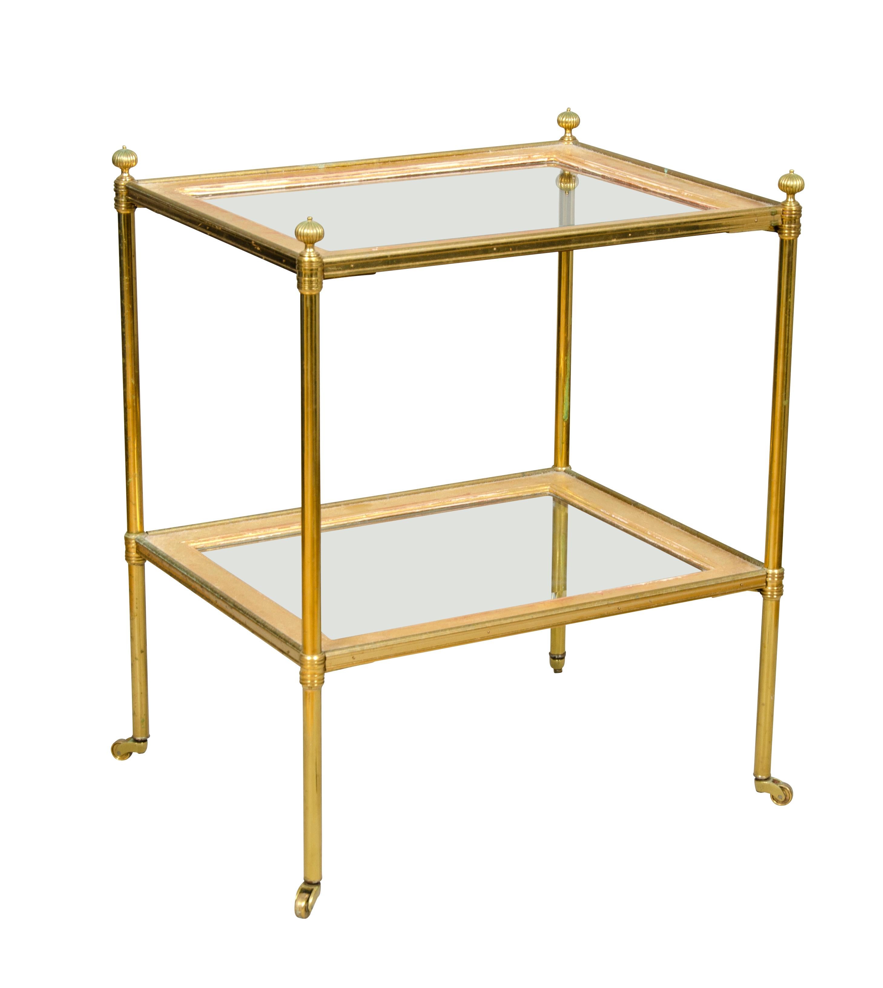 Rectangular with two tiers each with clear glass with gilt gesso border. Circular legs ending on casters.