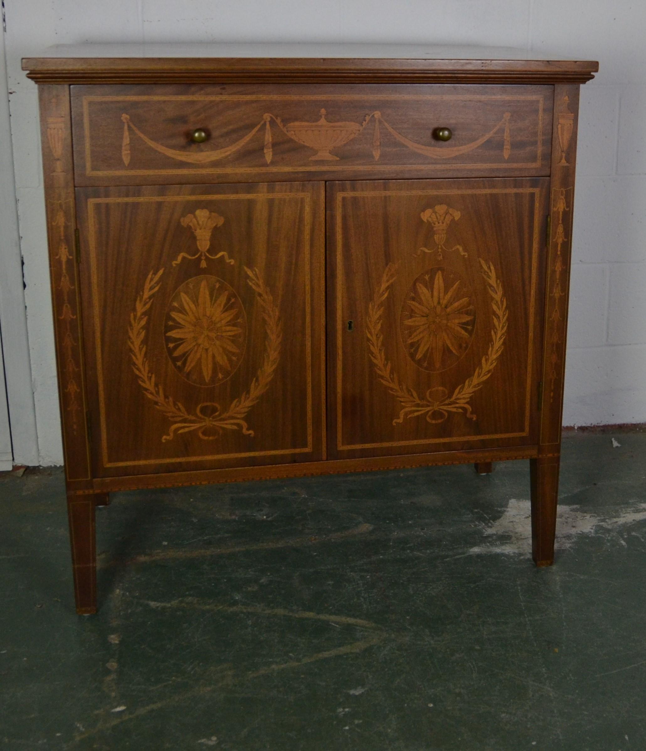 Edwardian style mahogany cabinet by Potthast Brothers. The single drawer and the two front doors have wood inlay. It comes with a key.