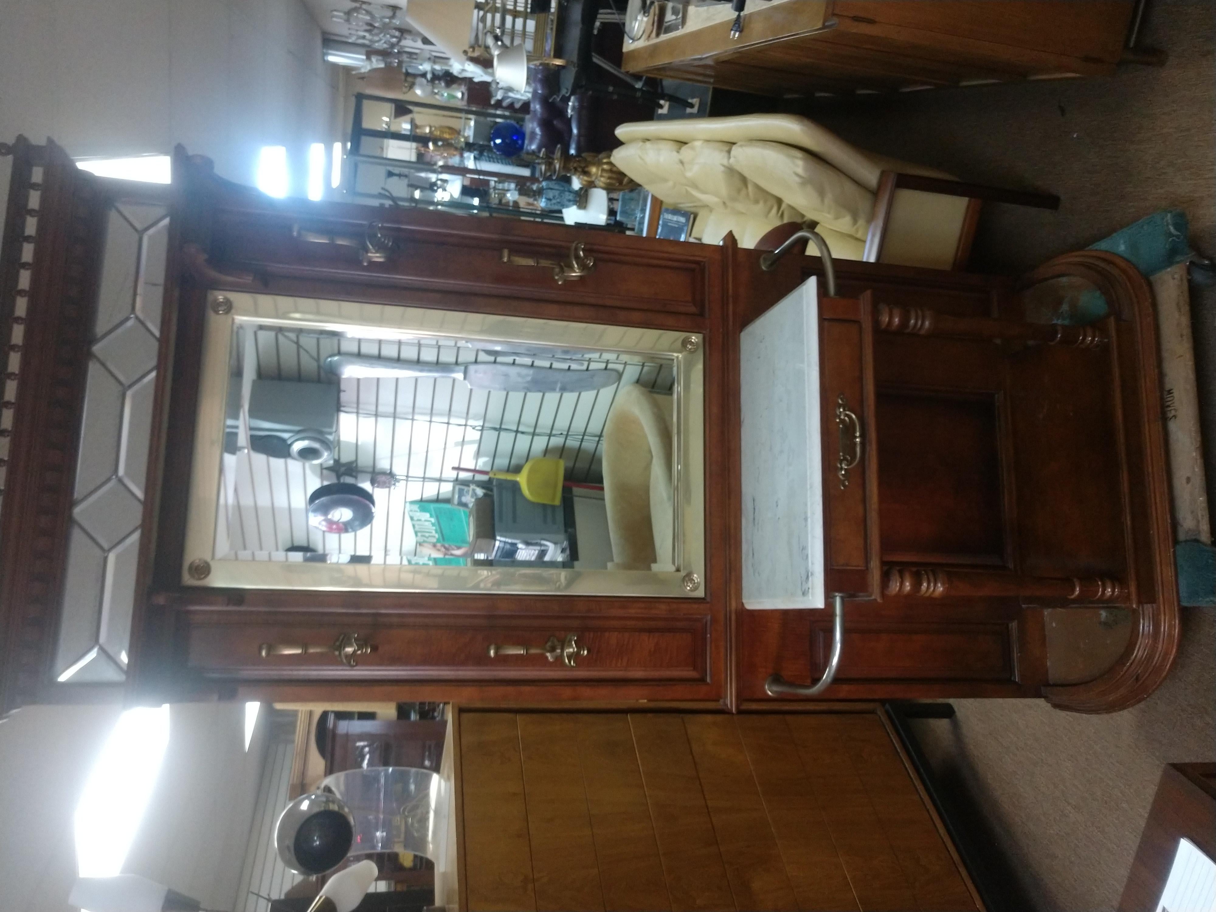 Fabulous style with so many functions. 4 coat hooks, drawer for storage umbrella or cane holders, hat rack shelf and a large brass framed mirror.
Top has a beveled leaded glass mirror above the caned hat rack shelf. Drawer for keys and gloves. Wood