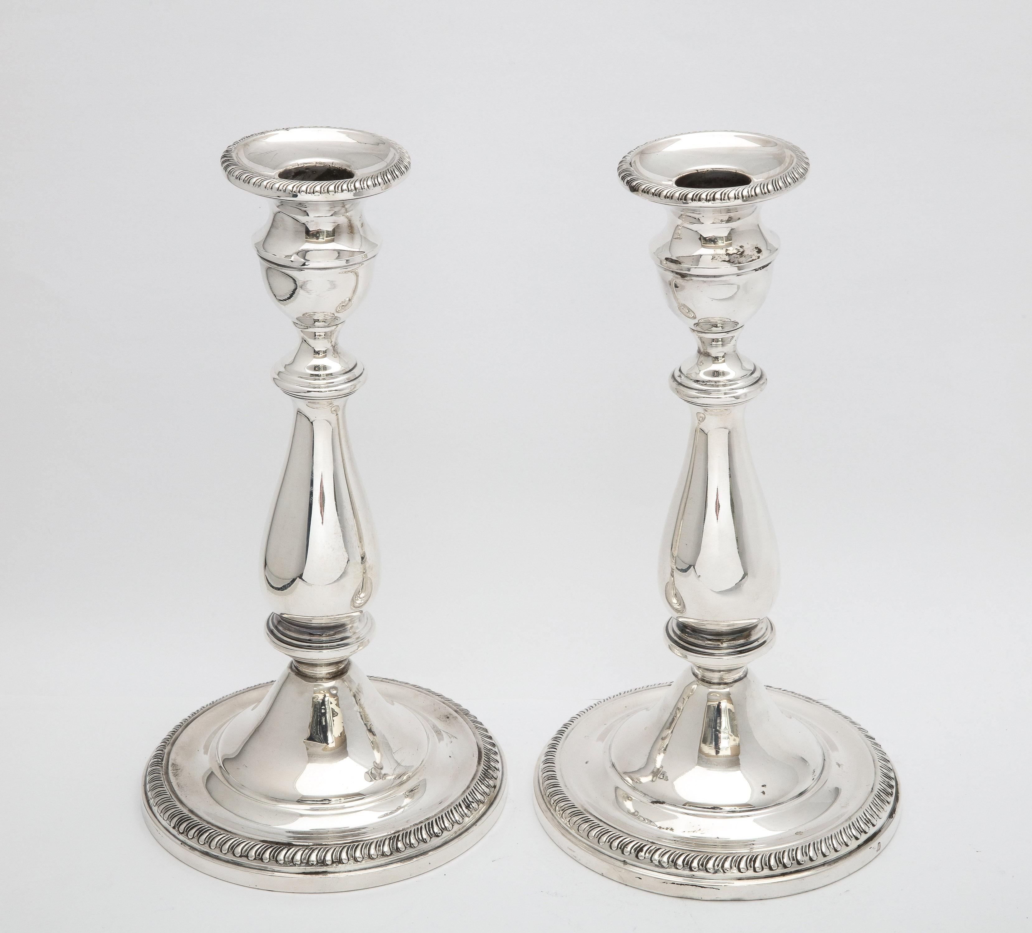 Edwardian style, sterling silver candlesticks, The Mueck-Carey Co., New York, Ca. 1940's. Each candlestick measures 9 inches high x 4 3/4 inches diameter and each is designed with  a reeded border circling its base and edge of its candle cup.