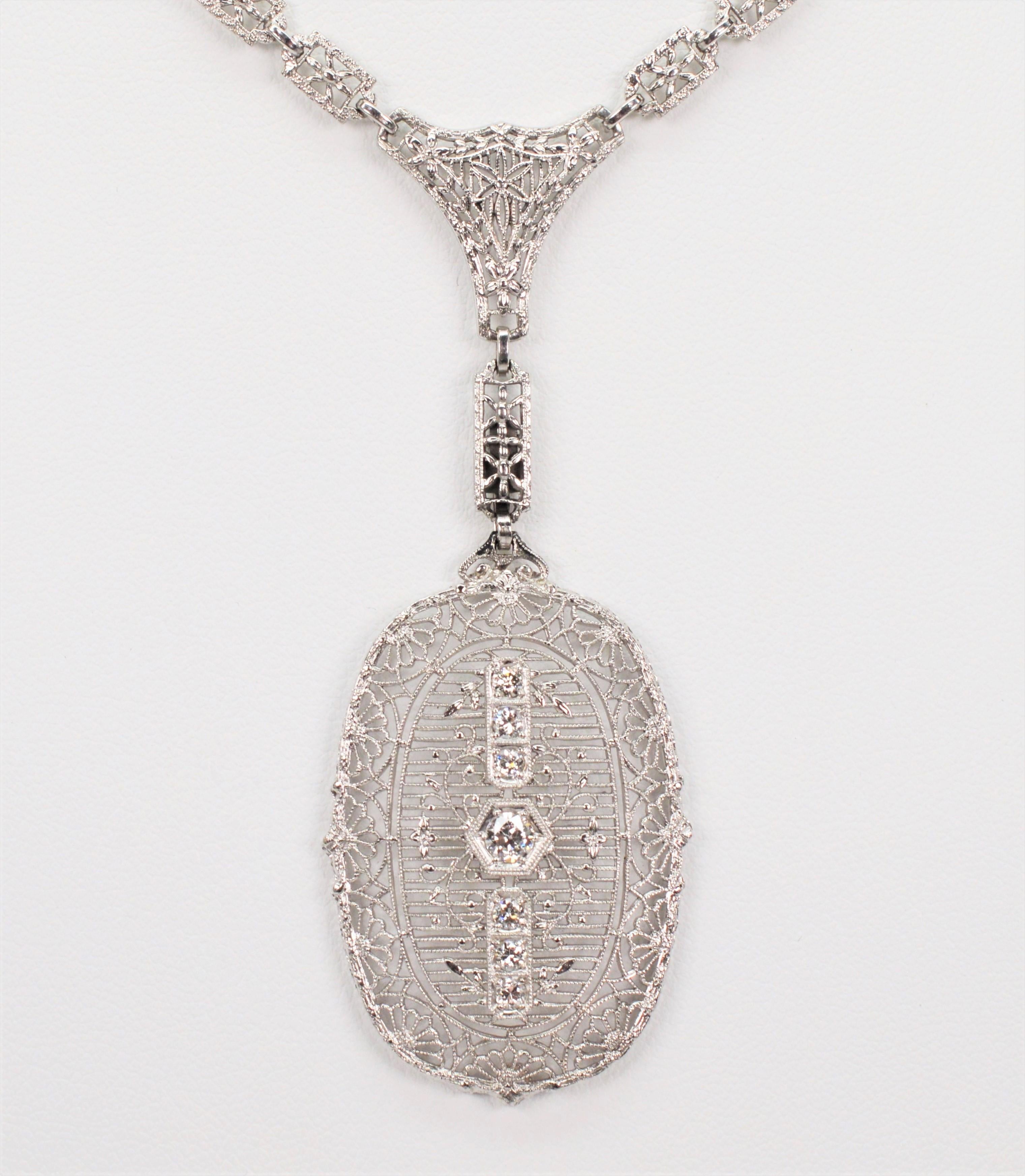 Five sparkling diamonds, .60 total carat weight , illuminate the intricate platinum and white gold filigree on this beautiful 1-5/8 inch oval pendant In the style of Edwardian finery, this stunning design is afixed and suspends from a 
period like