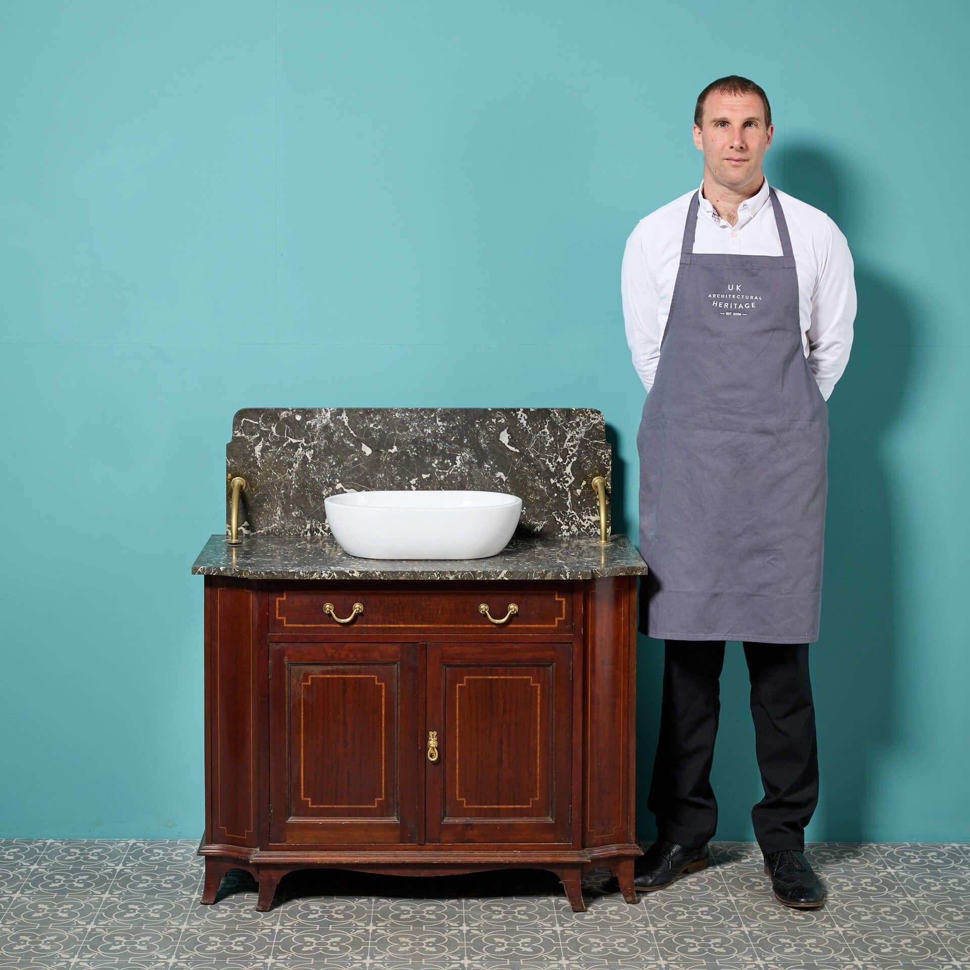 A handsome Edwardian style reclaimed mahogany washstand with a veined marble top and splash back. Offering plenty of bathroom storage and finessed with stylish brass hardware, this stunning washstand is supplied with a modern white ceramic bowl