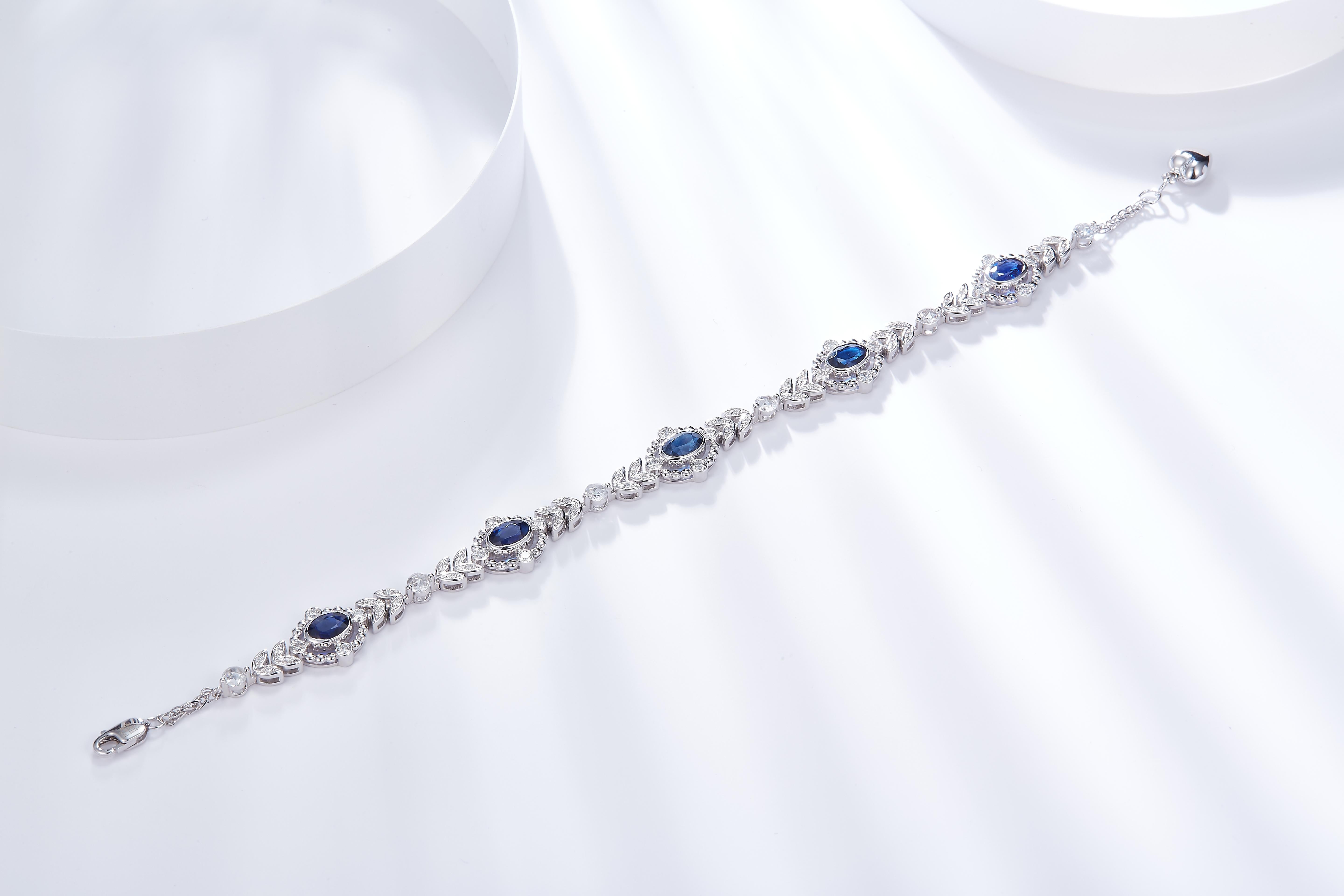 Dies ist ein Armband im edwardianischen Stil. Er ist mit 5 ovalen königsblauen Saphiren besetzt, die jeweils von einem Kreis aus Diamanten umgeben sind. Er verzweigt sich dann mit einem Blattmotiv, das durch einen einzelnen runden Diamanten