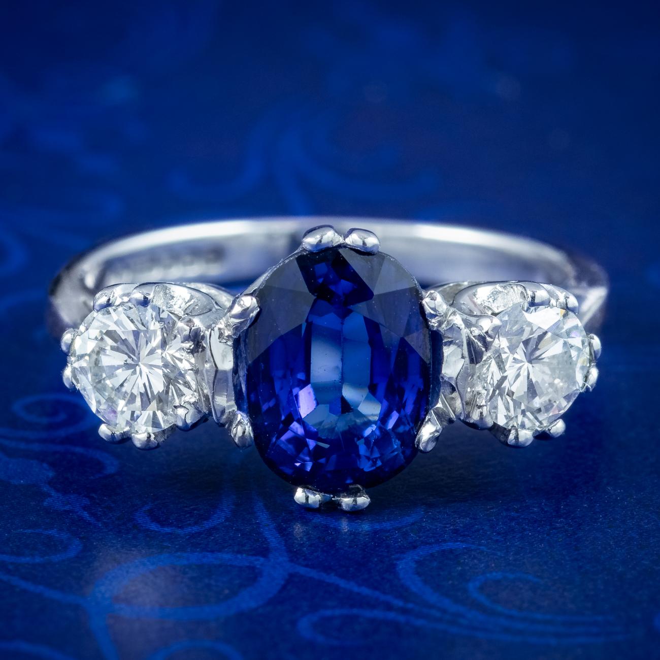 A stunning trilogy ring adorned with a striking oval cut sapphire in the centre weighing approx. 2ct, flanked by twin brilliant cut diamonds on either side, approx. 0.40ct each. The sapphire has a regal deep blue hue and is complemented beautifully