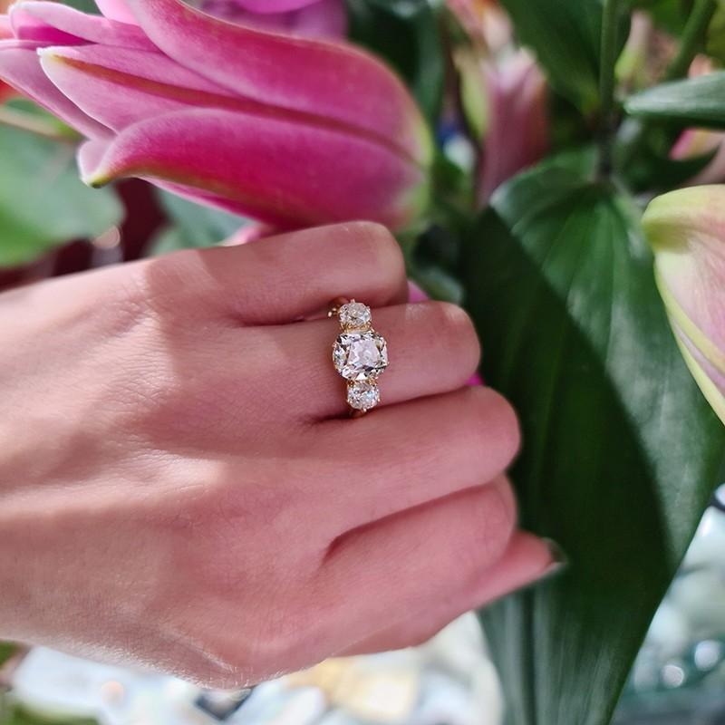 An Edwardian style three stone diamond ring, set with a 2.00ct, J colour, SI1 clarity cushion old mine-cut diamond, with cushion old mine-cut diamonds set either side, with a total weight of 0.87ct, which in our opinion are H colour, in claw