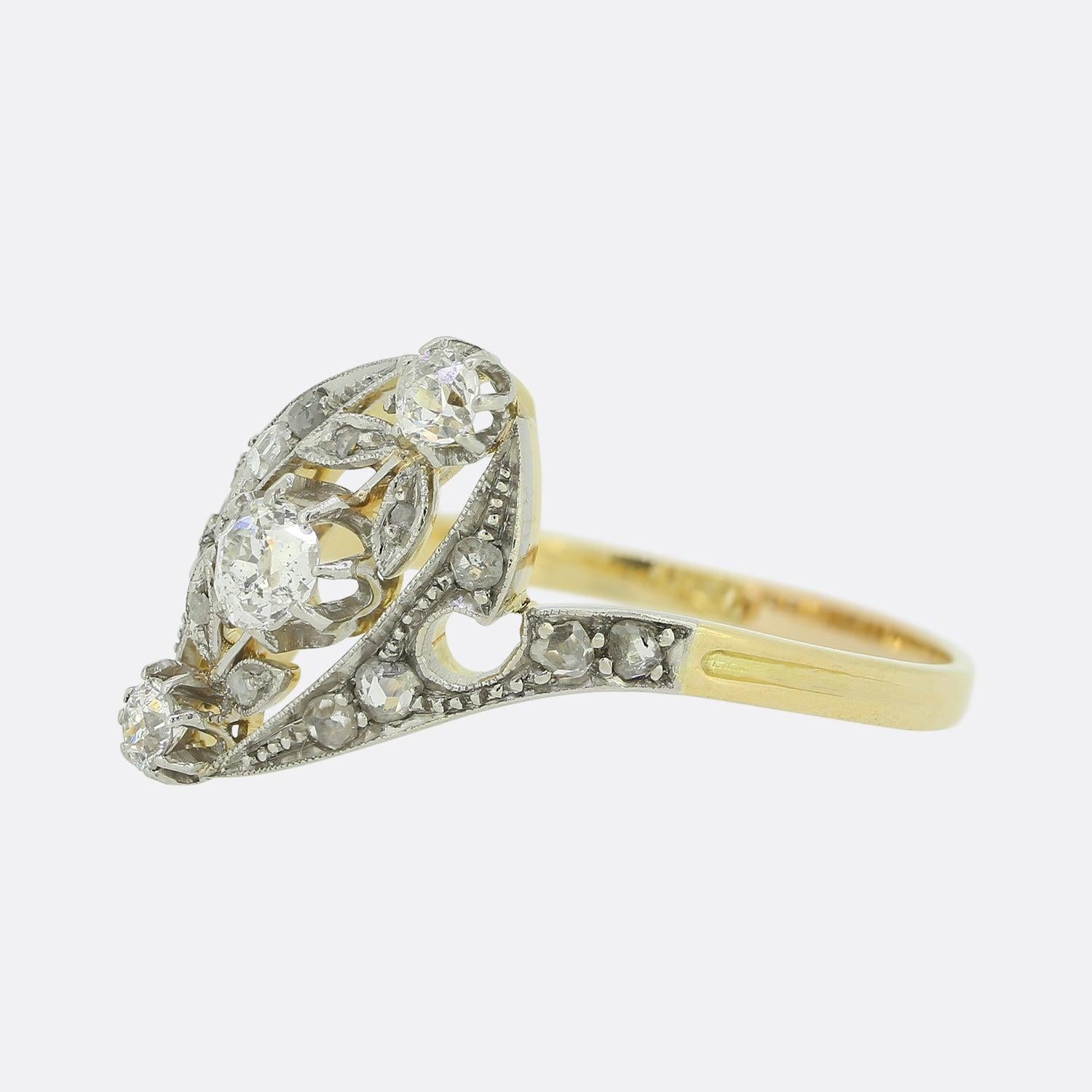 This is an Edwardian 18ct yellow gold and platinum diamond three stone twist ring. The ring features three old cut diamonds which have been claw set in platinum at the centre of two elegant crossover bands. The diamonds are well matched for colour