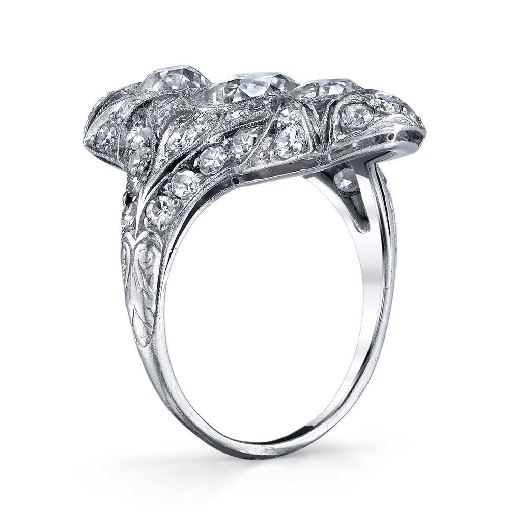 Circa 1910: this stunning three stone diamond ring from the Edwardian era features a 1.65 carat European cut diamond in the center. Complementing the center diamond are 1.65 carats of European cut diamonds.  At the turn of the century jewelers