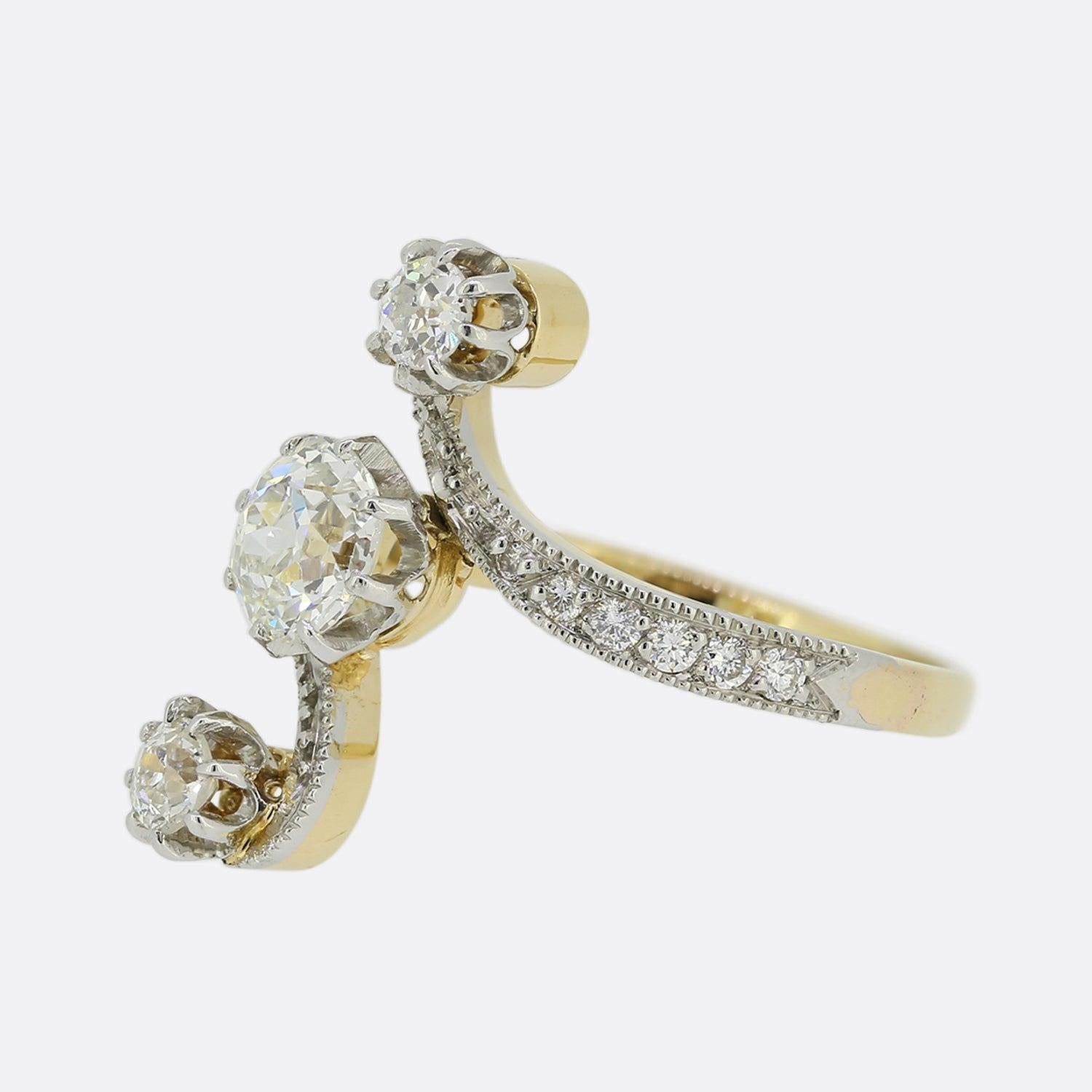 This is an elegant upfinger ring from the Edwardian era. Each centralised stone here is of a high quality and is accentuated by a beautiful swirling motif on either shoulder. A beaded white gold bordering graduates inwardly in size and encapsulates
