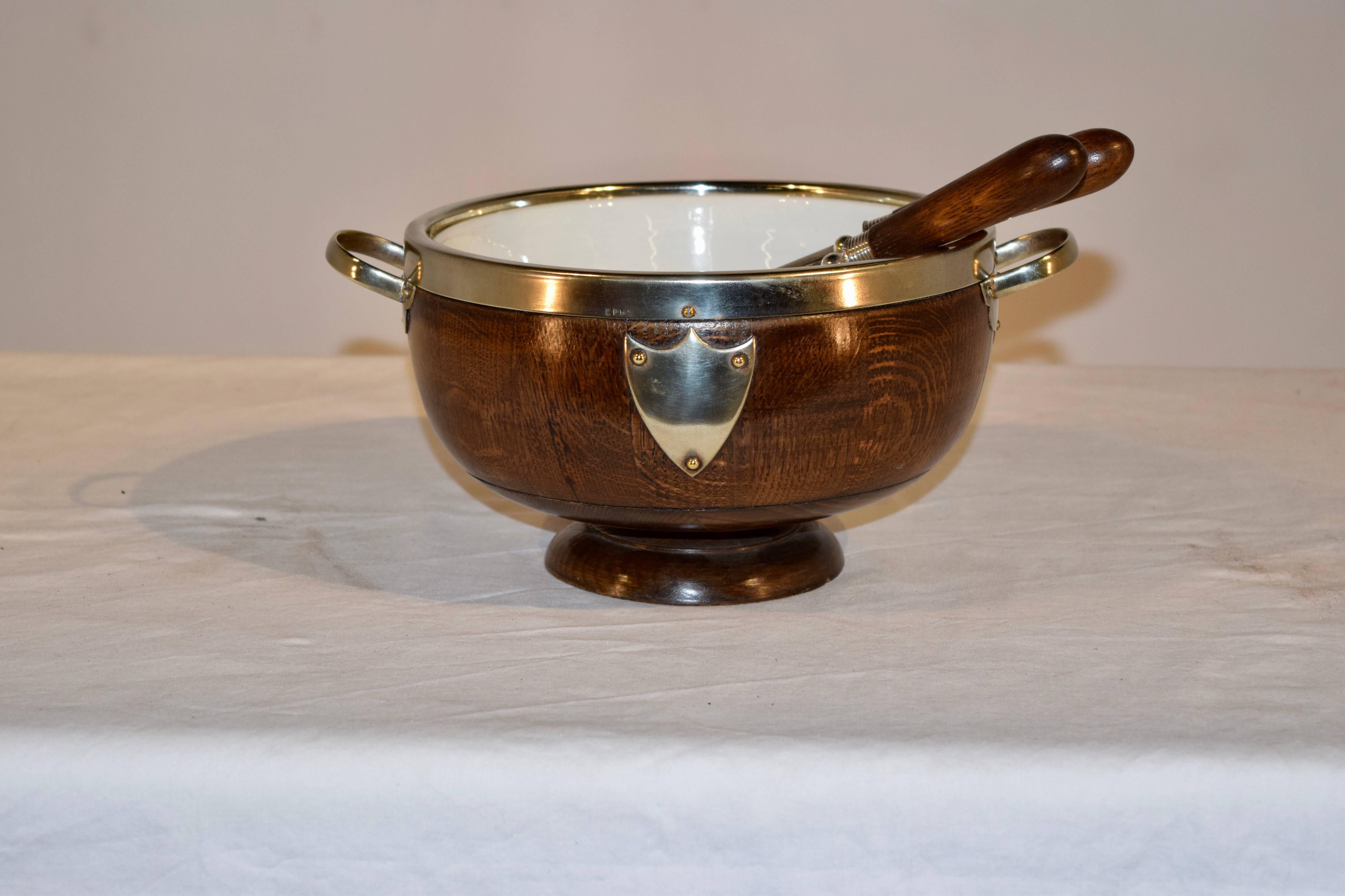 English oak treen serving bowl with original porcelain liner and pair of salad servers. The bowl is nicely hand turned and is banded in silver-plate. The servers are 10.75 inches in length.