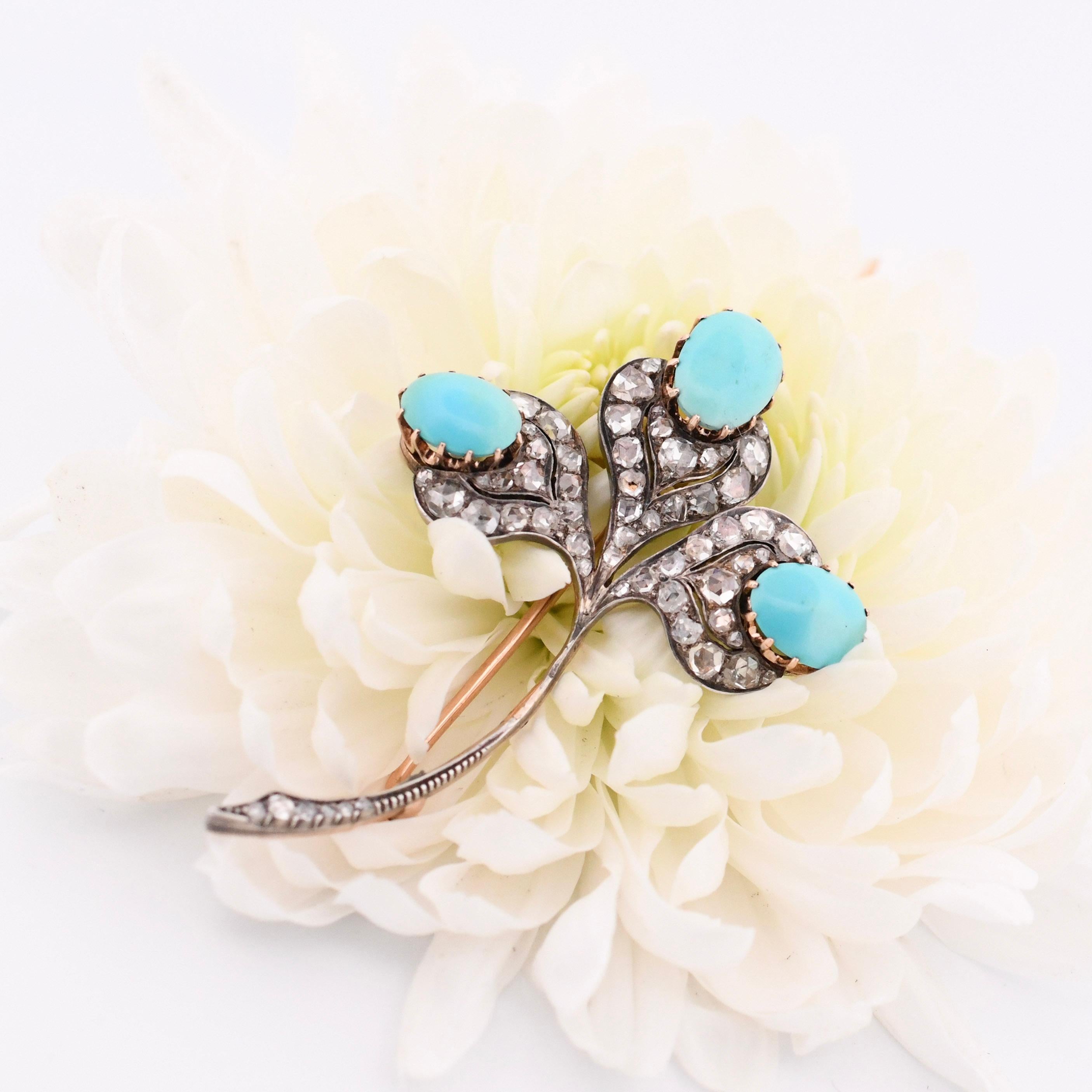 Introducing a stunning Art Deco brooch that exudes timeless elegance and charm. This exquisite piece features a clover-shaped design adorned with three captivating turquoise cabochons and dazzling rose-cut diamonds, all set in 14K yellow gold. The