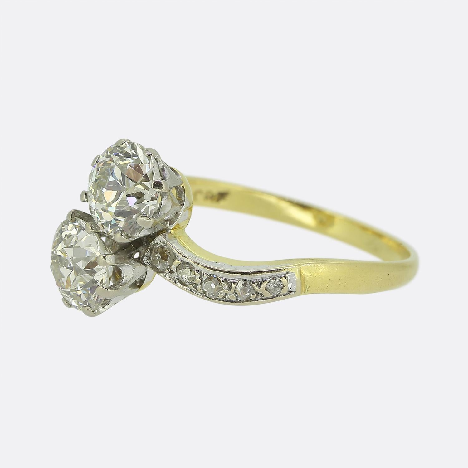 Here we have a delightful two-stone ring dating back to the Edwardian era. This antique piece showcases two bright white round faceted old European cut diamonds; both of which sit proud in a slight diagonal fashion atop a twisted backdrop. Five