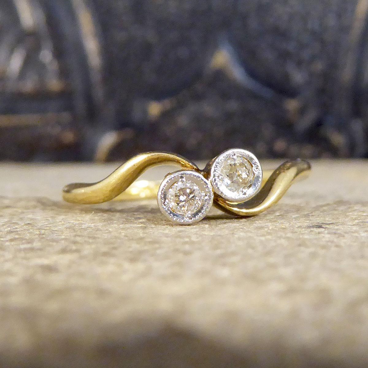 A very elegant two stone diamond twist ring that is set with two sparkling diamonds weighing a total of 0.15ct. The stones are set in Platinum rub over collar setting on the top with a milgrain detail, a typical style setting for an Edwardian ring.