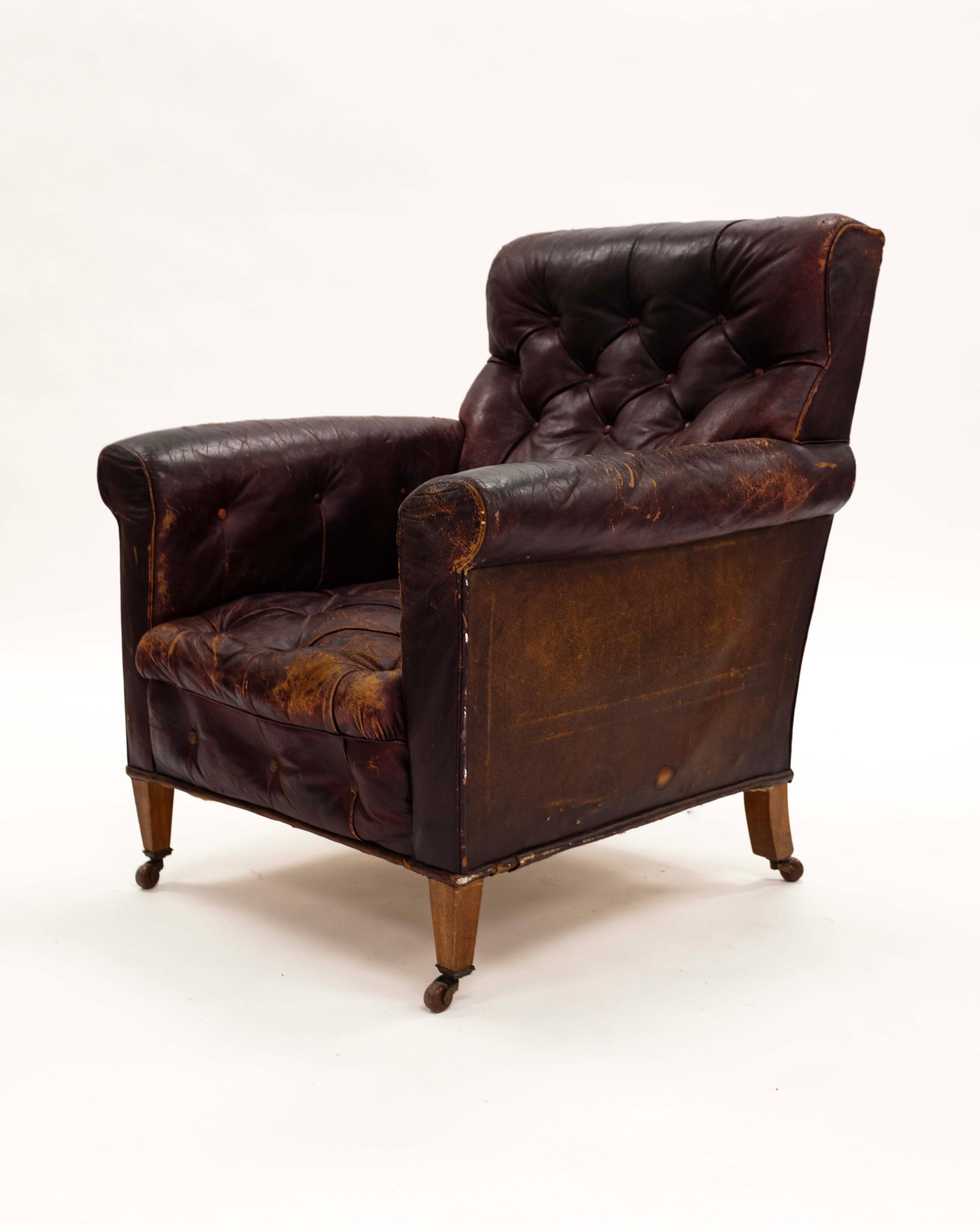 Edwardian vintage tufted leather library chair with casters in original leather.  Leather is cracked and worn with a tear in the back .
