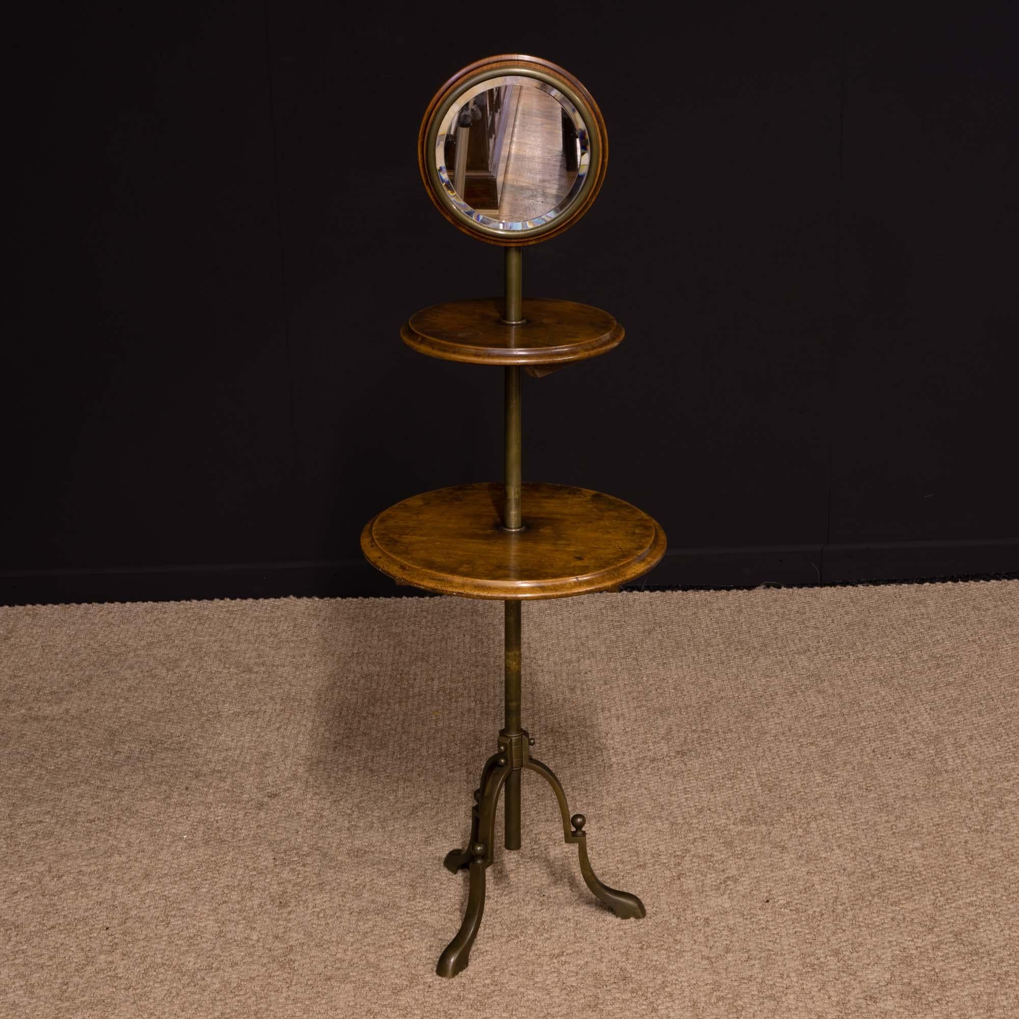 A very unique Edwardian Gentlemen's shaving stand, the legs and telescopic central column are brass foil on solid steel and the two shelves are solid walnut. The bevelled round mirror has a very unusual feature being a combination of walnut with a