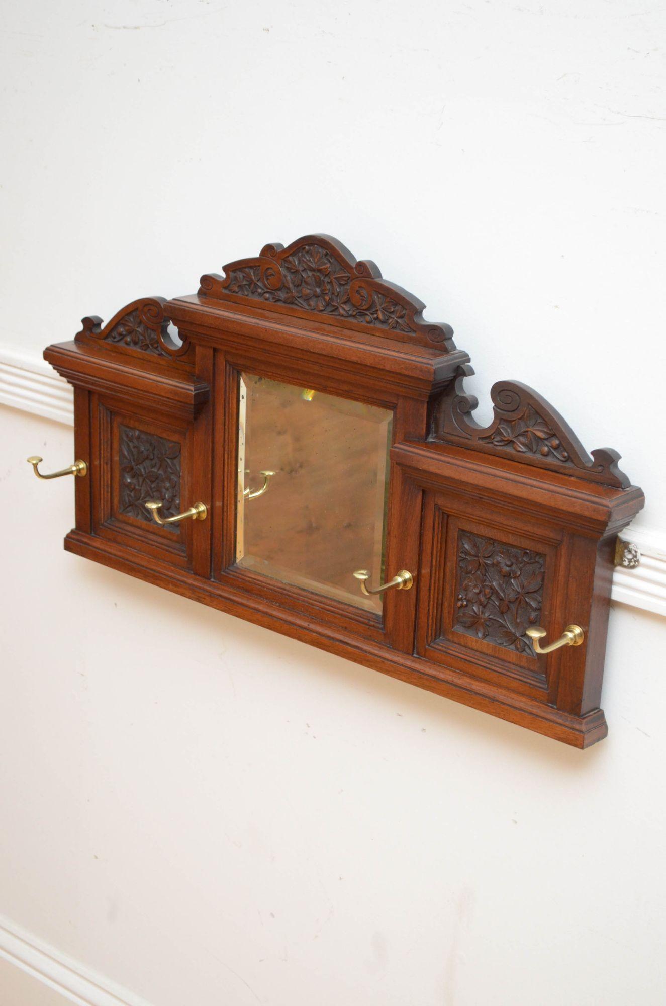 P0294 Stylish Edwardian coat rack in walnut, having finely carved triple upstand above original bevelled edge mirror flanked by decorative floral carved panels, all fitted with four projecting brass hooks. This antique coat rack retains its original