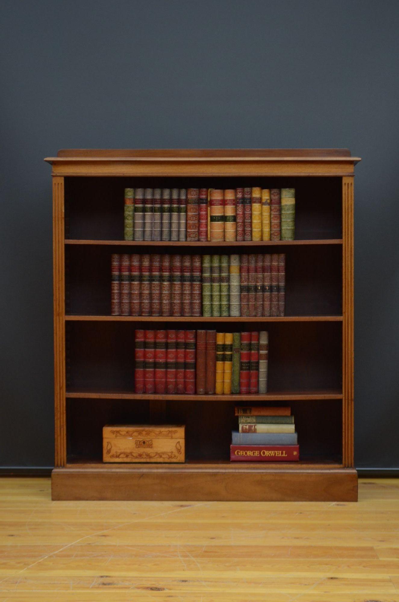 K0622 Edwardian open bookcase in walnut, having shaped upstand to the back edge, figured walnut top with moulded edge and shallow frieze above three height adjustable shelves flanked by reeded pilasters, all standing on moulded plinth base. This