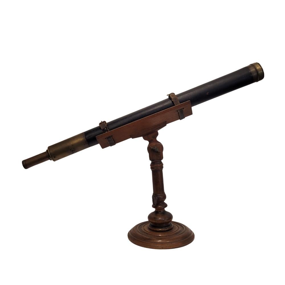 Elegant and timeless  French table refractor telescope from the early 20th century. It features a circular turned wooden base and a shaft that supports the main body, held in place by two leather straps. The optical tube is cylindrical, made of wood