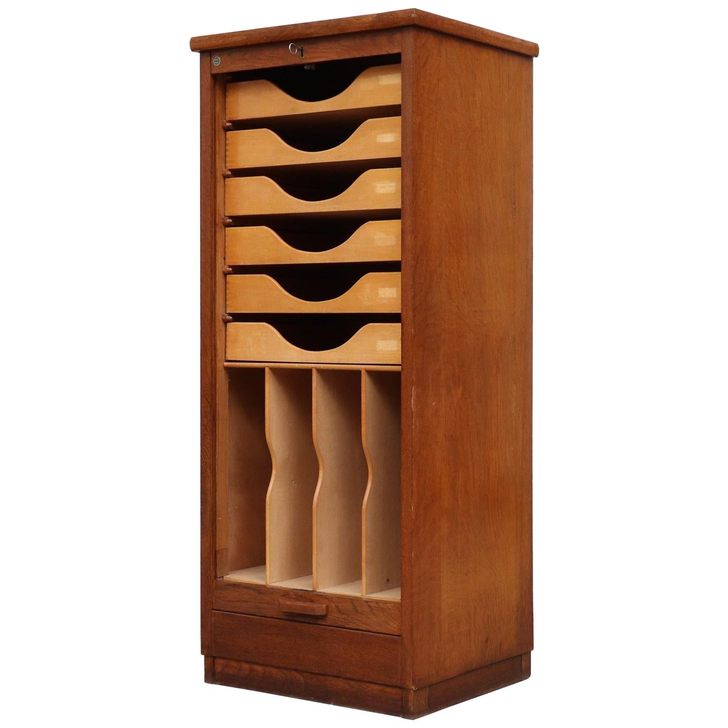 Eeka teak file cabinet with tambour door. Lightly refinished. 6 drawers, 4 record or file slots. In original condition with some visible signs of wear consistent with age and use. Self locking, key included.