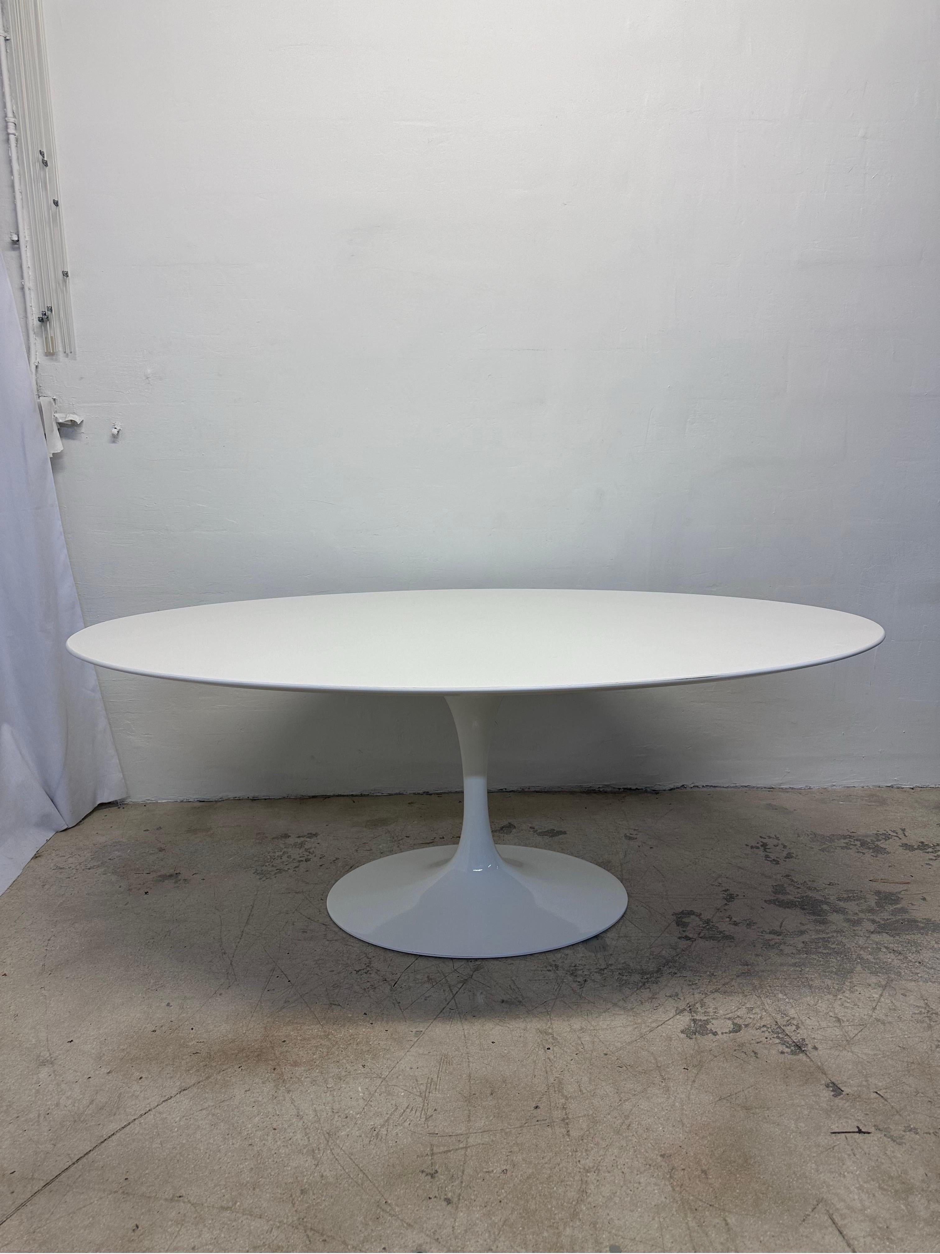 White laminate oval 78” top with white lacquered tulip pedestal base dining or center table designed by Eero Saarinen and manufactured by Knoll International. Maintains Knoll label.  Edges and top show wear and loss.