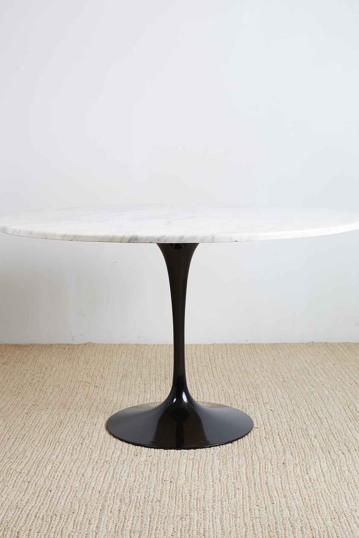 Dramatic Carrara white marble top tulip table featuring a contrasting black metal base. Designed by Eero Saarinen for Knoll. Signed, stamped, and dated on base of table on top and bottom. Iconic lacquered aluminum base supports a 48 inch diameter