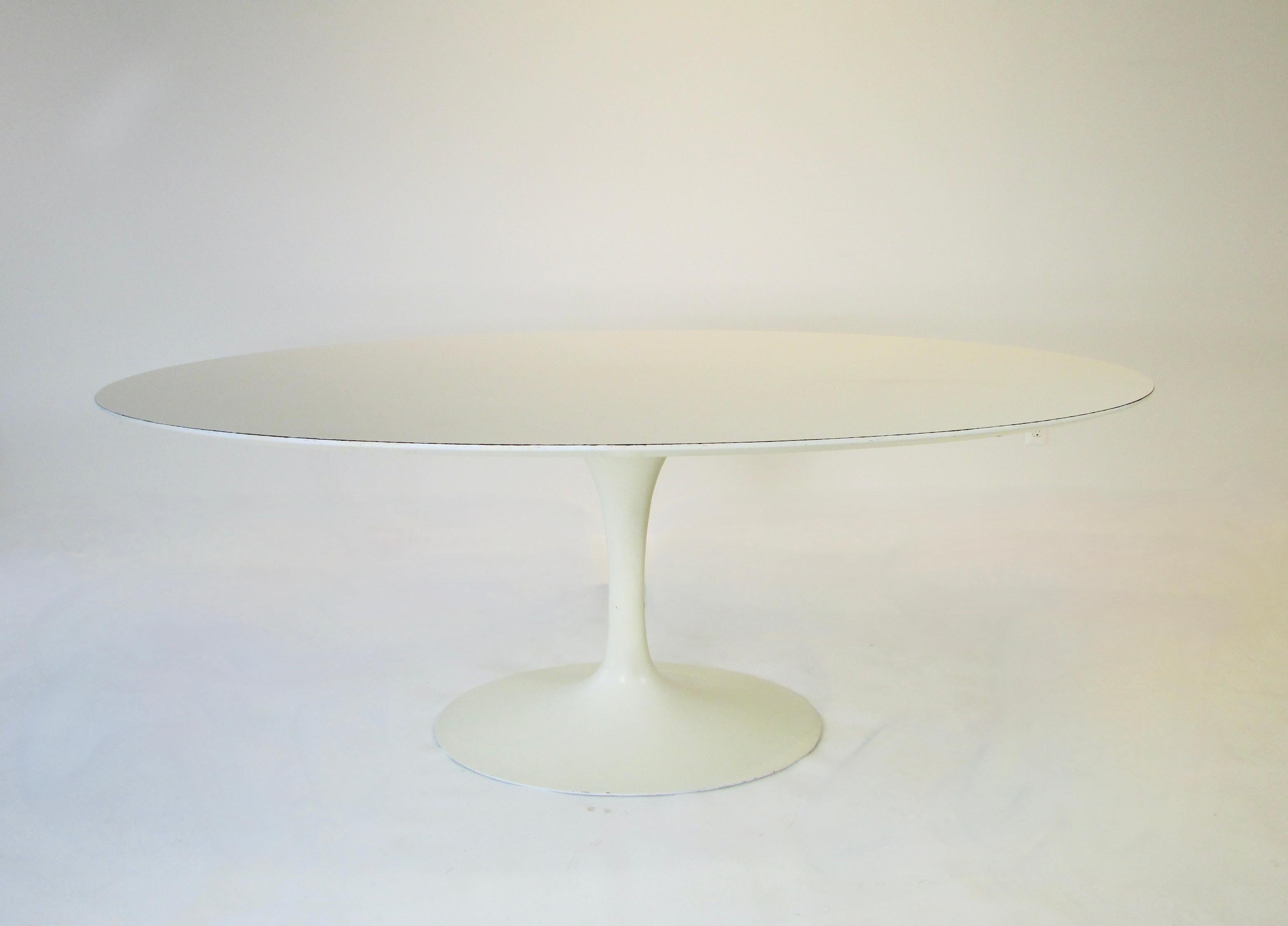 Earlier production Eero Saarinen Knoll cast iron base Tulip group dining table. White laminate top on lacquered base. Retains original label on underside . No chips or cracks to laminate top . 