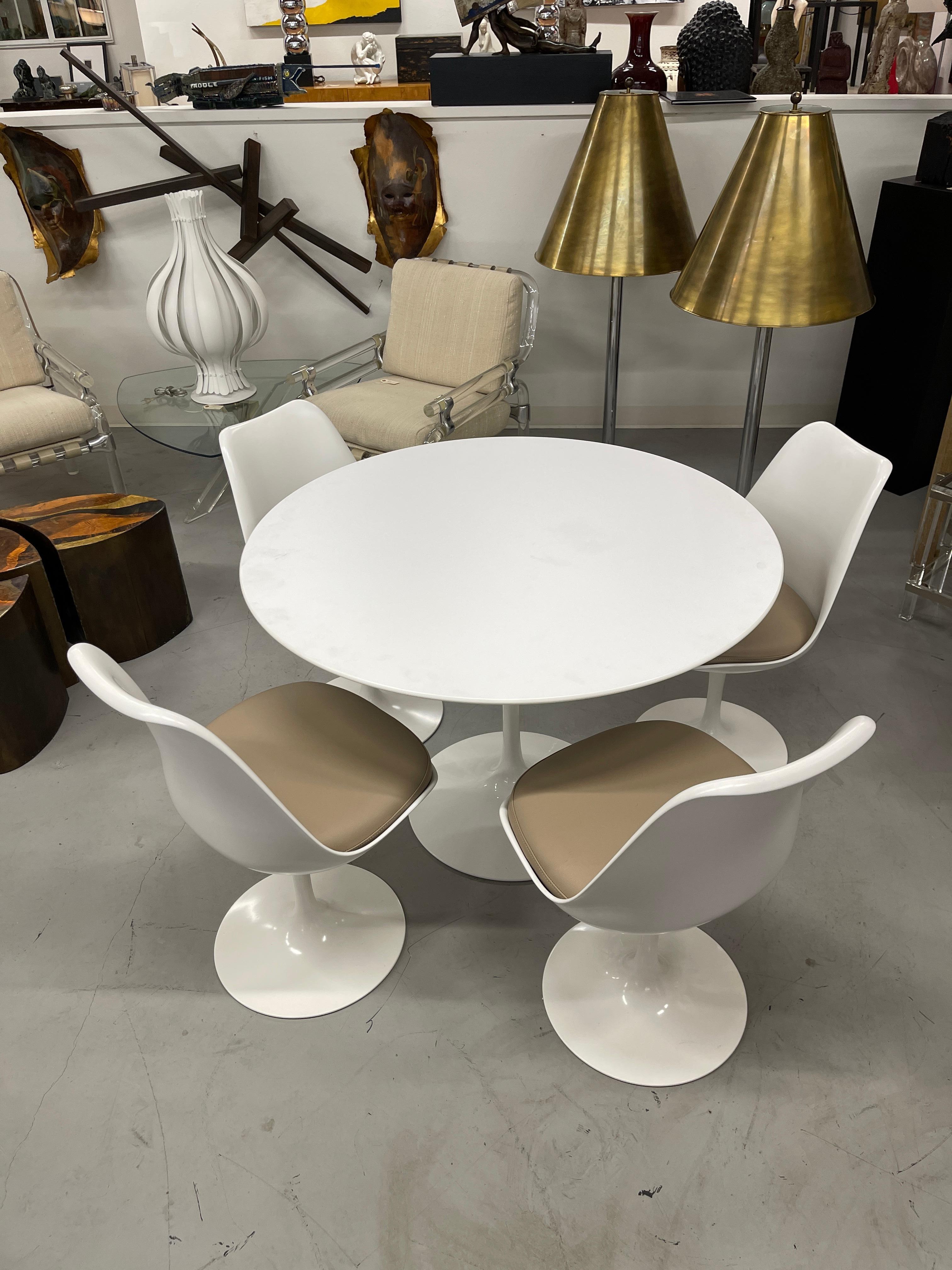 Eero Saarinen for Knoll Pedestal Tulip table with four chairs. The chairs have leather cushions and Knoll tags dated 2015. The set has seen very little use and is in good condition. The table bears the Knoll tag as well. Table is 42 inches in