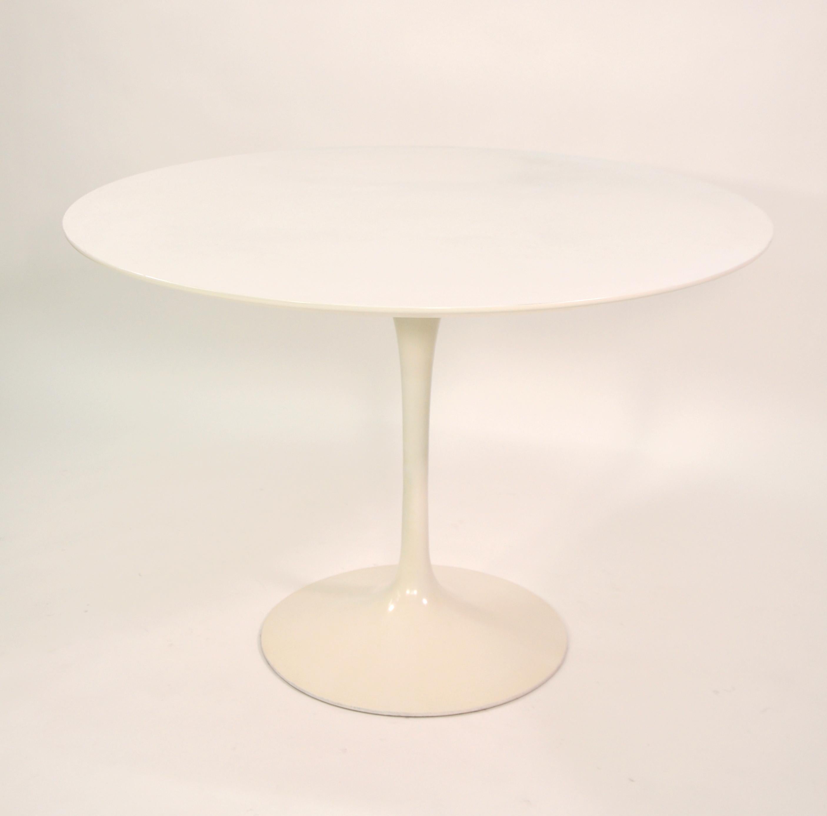 A vintage 1960s Mid-Century Modern off-white round pedestal dining table designed by Eero Saarinen for Knoll. The tabletop is 42 inches and features a white top which allows for ease of use and care. The pedestal base is cast aluminum. The Tulip