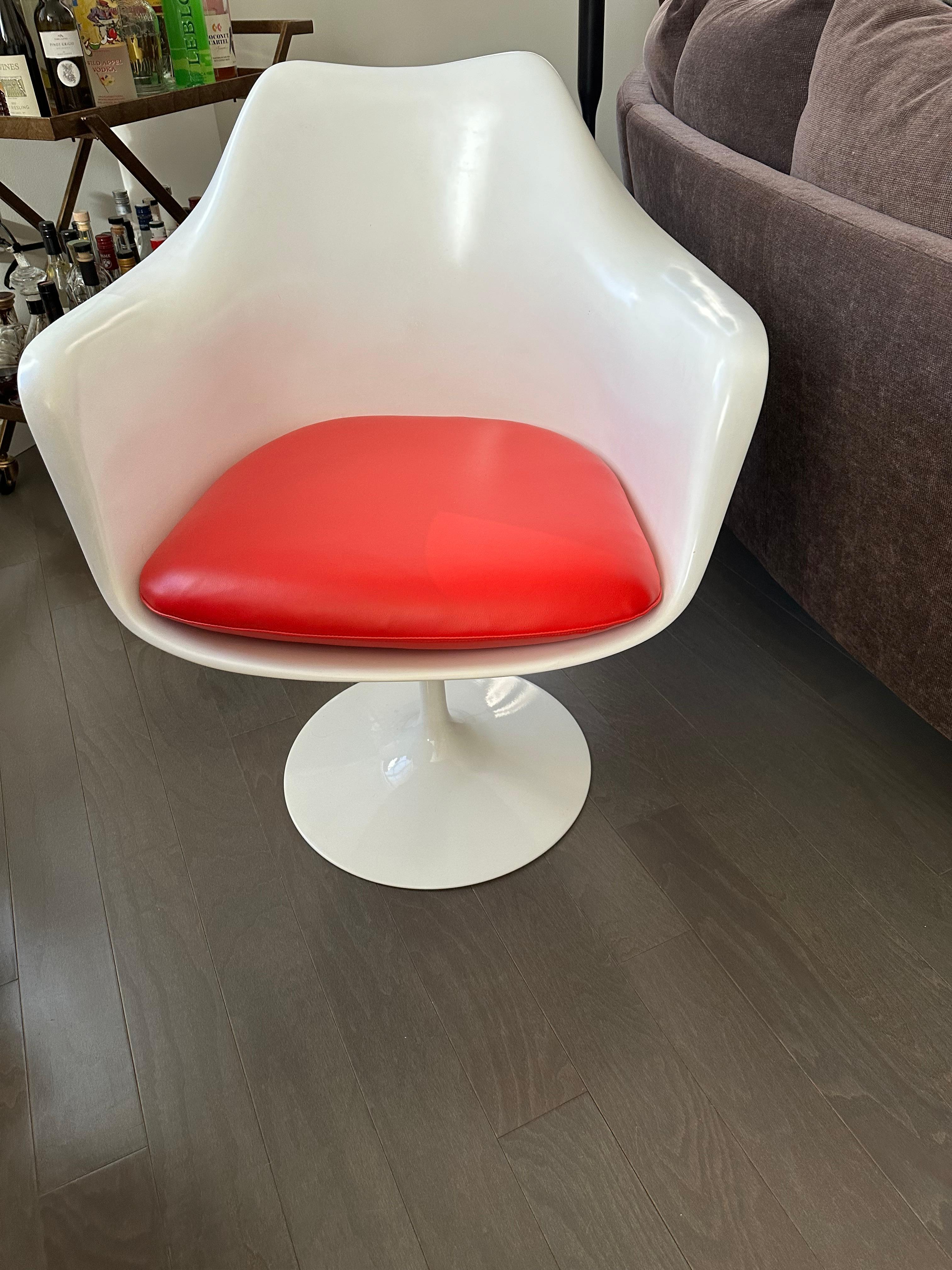Designed by Saarinen for Knoll ca. 1955. This set is from the early 2000s, in incredible condition and includes iconic red vinyl cushions on its four swivel chairs - two with arms, two without. Table measures 42” by 28” and chairs 20” and 26