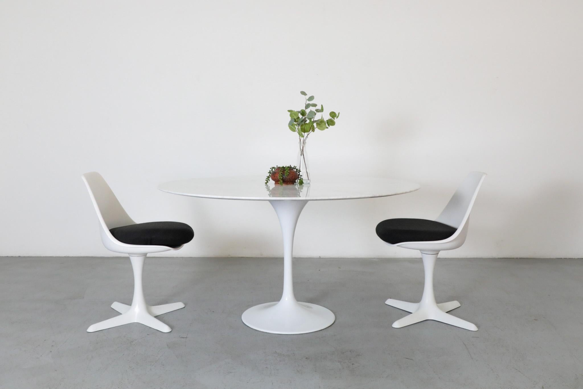 Mid-Century white marble dining table with white tulip base in the style of Eero Saarinen, produced by France & Son. The table has visible wear and staining, including water rings and spots. Wear is consistent with its age and use. Shown with 2