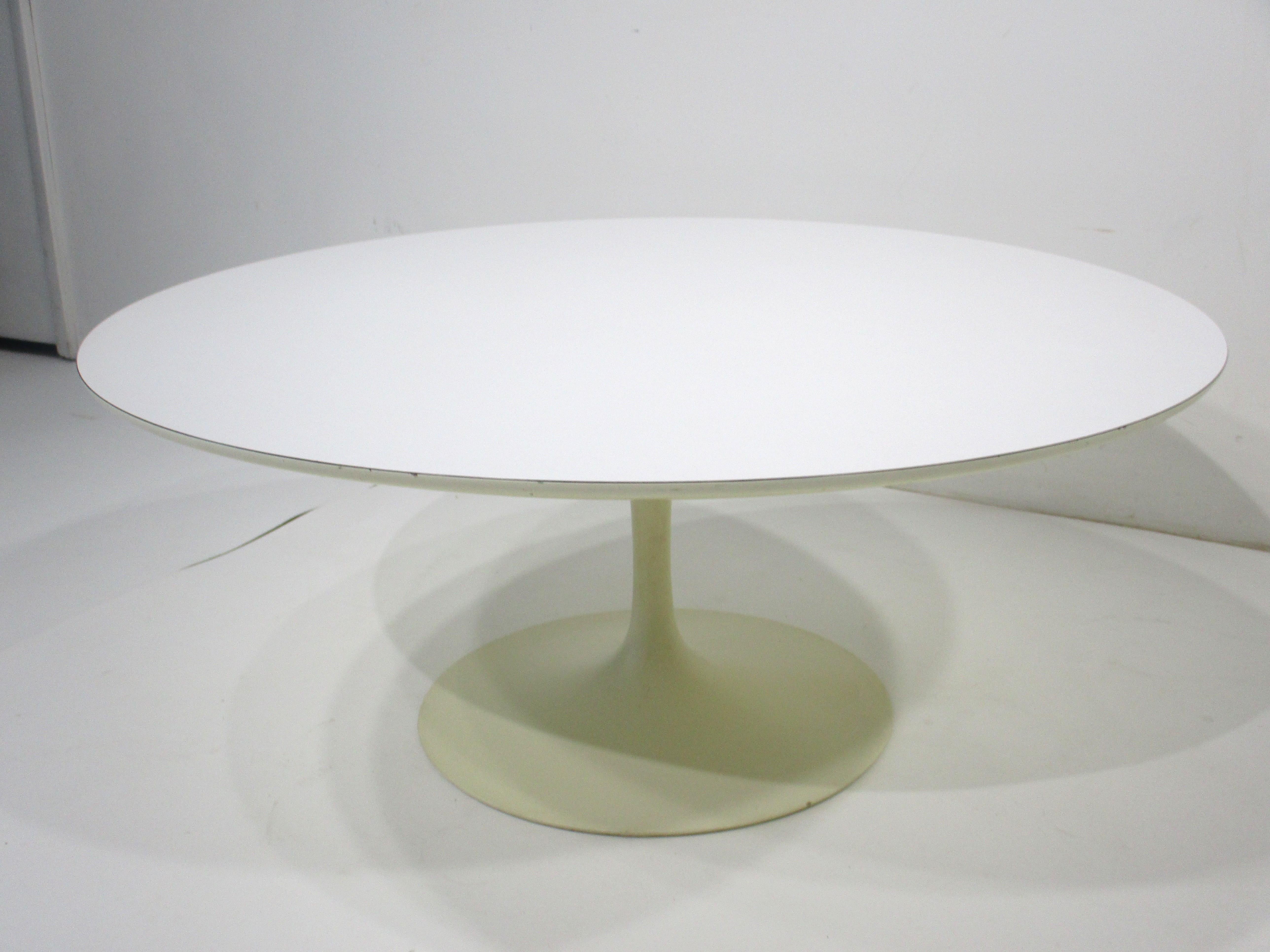 A sculptural white tulip coffee table with steel base and Laminate top by designer , architect and artist Eero Saarinen . This iconic table has been a mainstay of the Mid Century modern design movement since it's inception and is still fresh today .