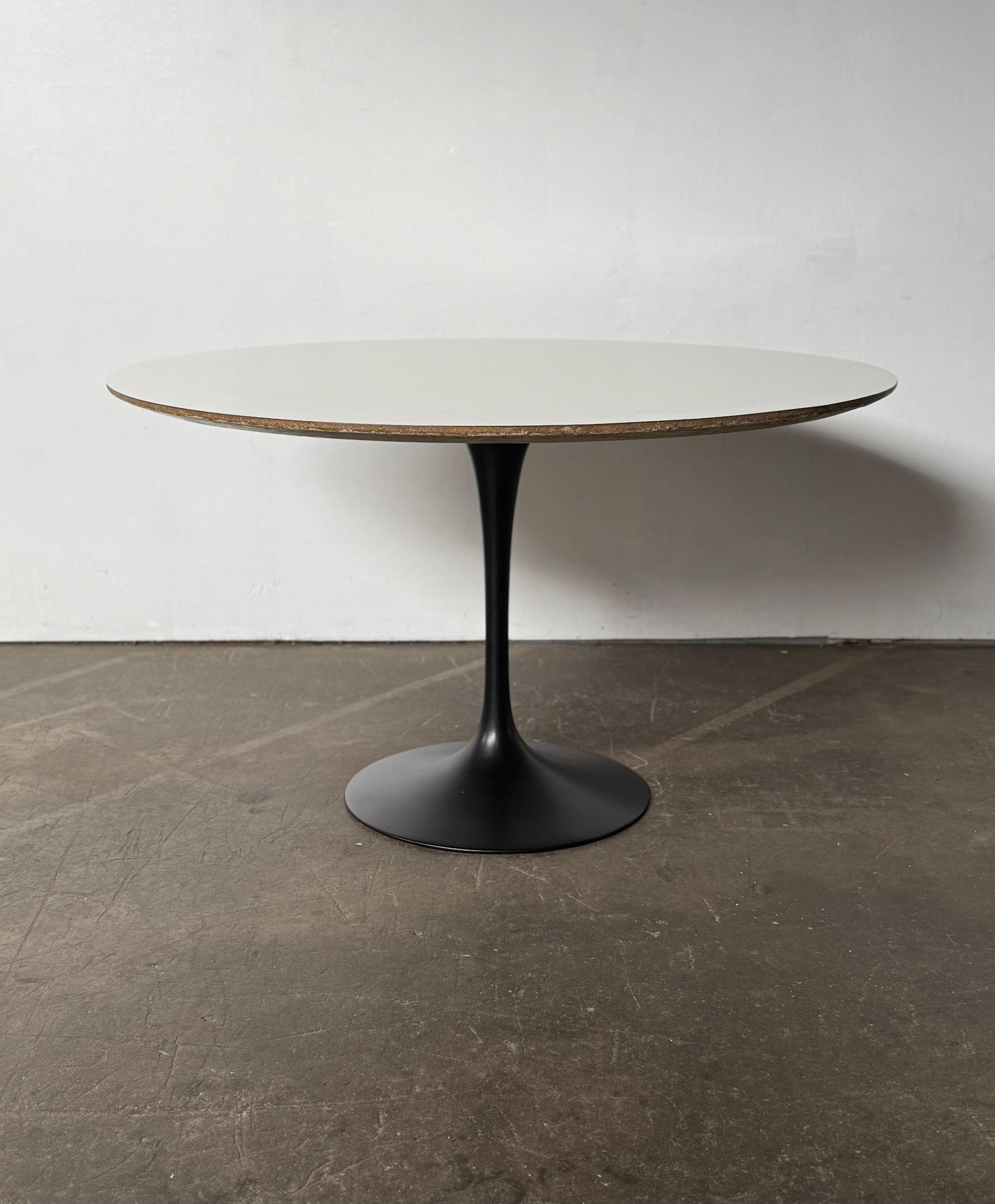 Classic Eero Saarinen tulip dining table for Knoll. 48 inches in diameter, accommodating 5-6 side chairs or 4 armchairs. White round laminate top and black satin finished cast aluminum pedestal base. Both are in good condition. Normal age related