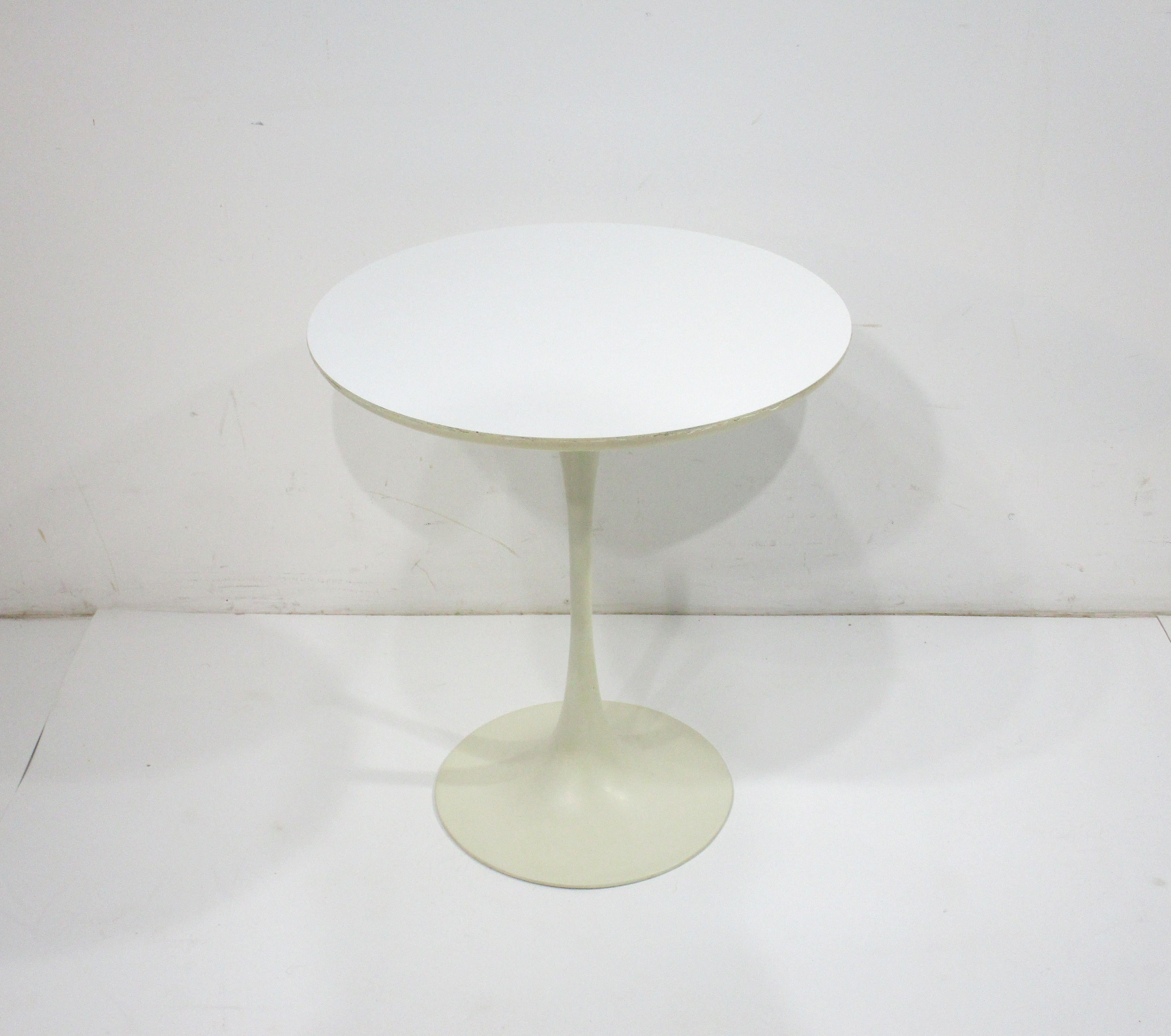 A vintage tulip side table with round Laminate top having a nice soft curved edge . The heavy sculptural cast metal base makes the table very sturdy and in a cream white makes this iconic piece of Mid Century design a true timeless classic .