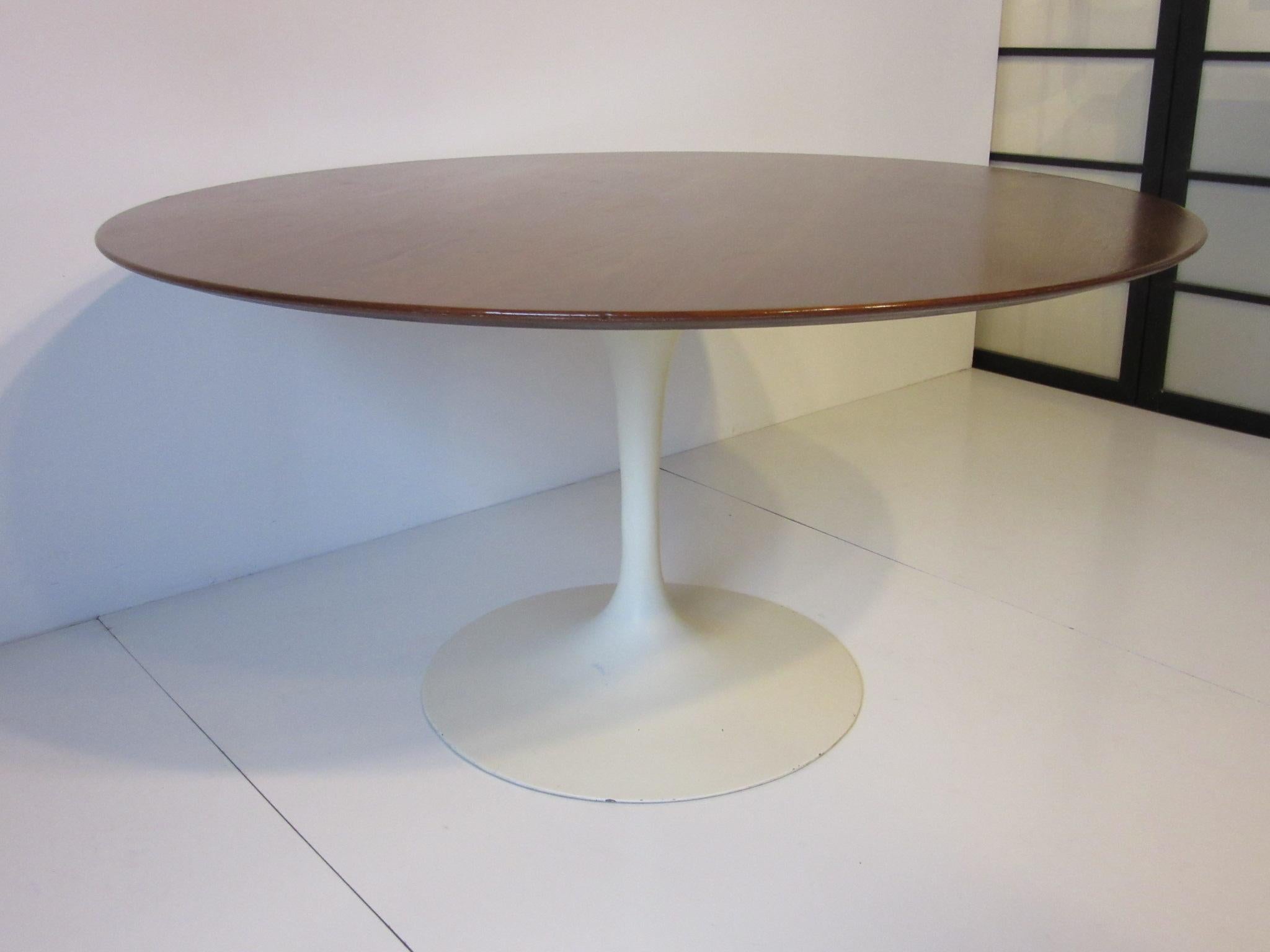 A well grained round walnut topped dining table with beveled edge and off white metal base, an earlier example that retains the original manufactures label to the bottom. Knoll Associates, Madison Ave. NY.